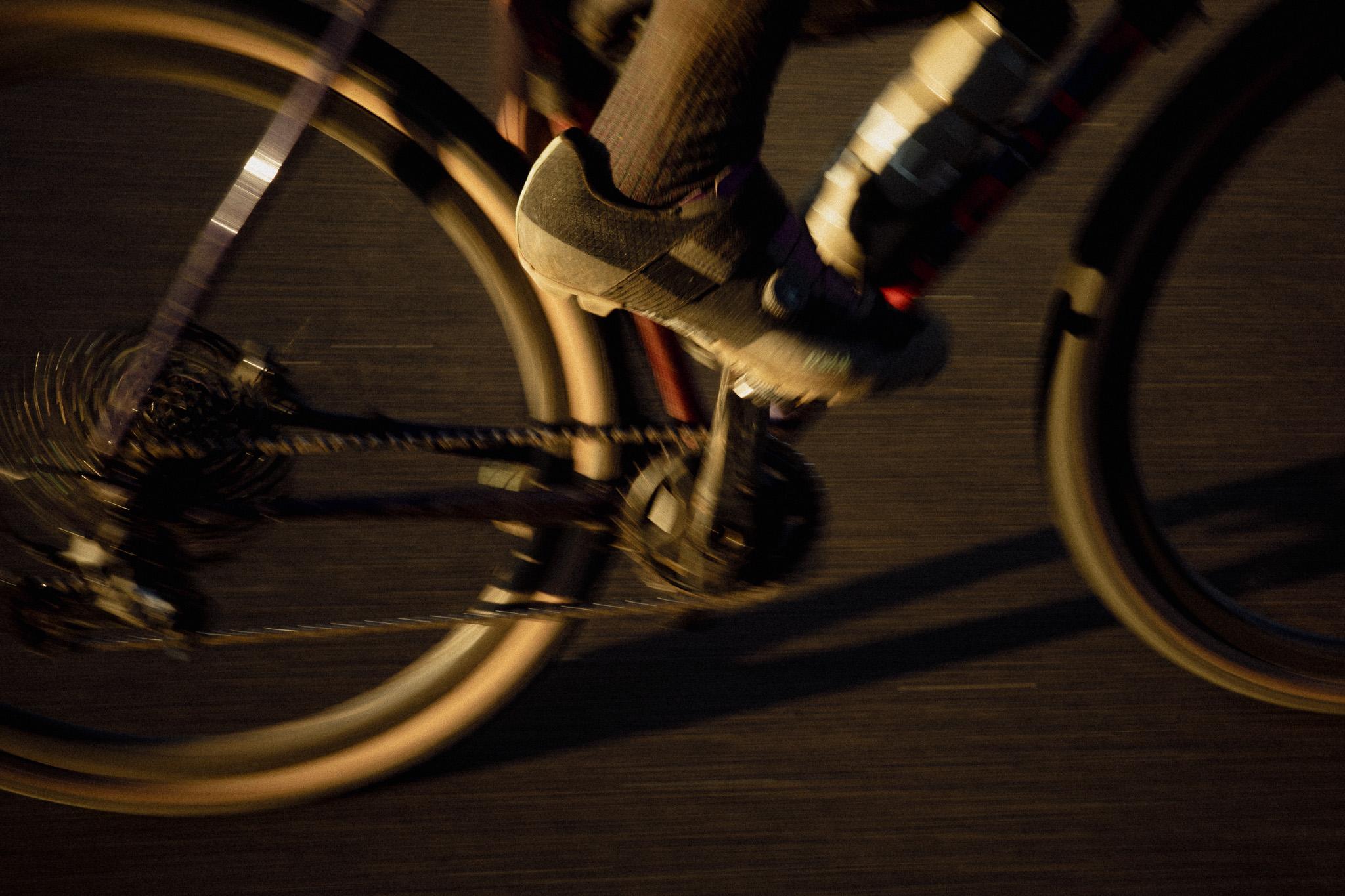 Cyclist in motion with wheel blur and dramatic lighting on road surface