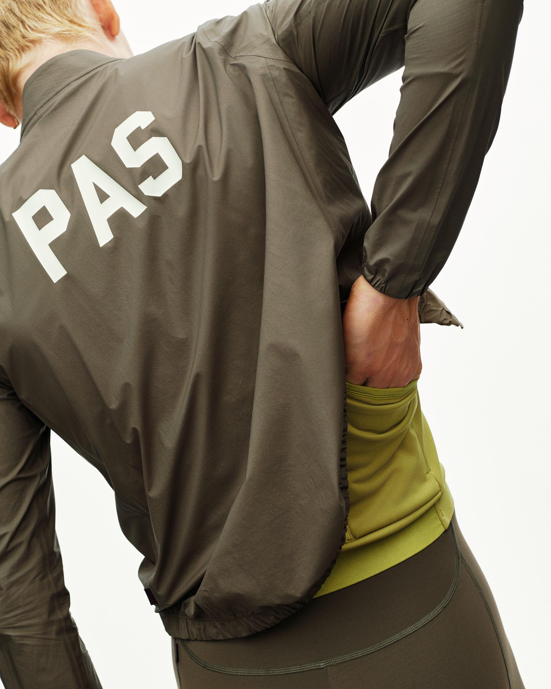 Dark Earth khaki PAS Mechanism cycling rain jacket on model, rear view with white PAS back print