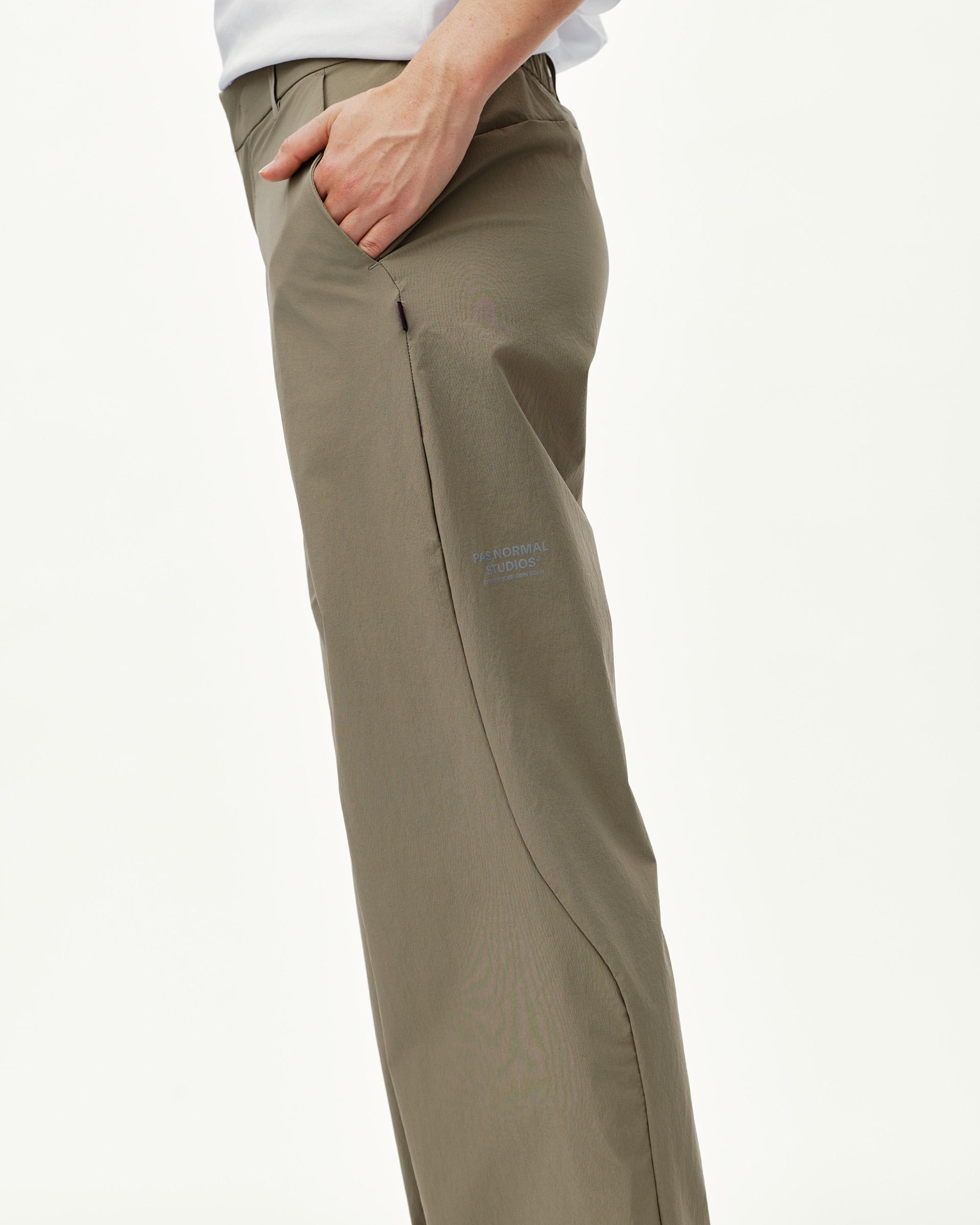 Dusty Earth khaki Off-Race Tech pants on model, side view with curved seam and zip pocket
