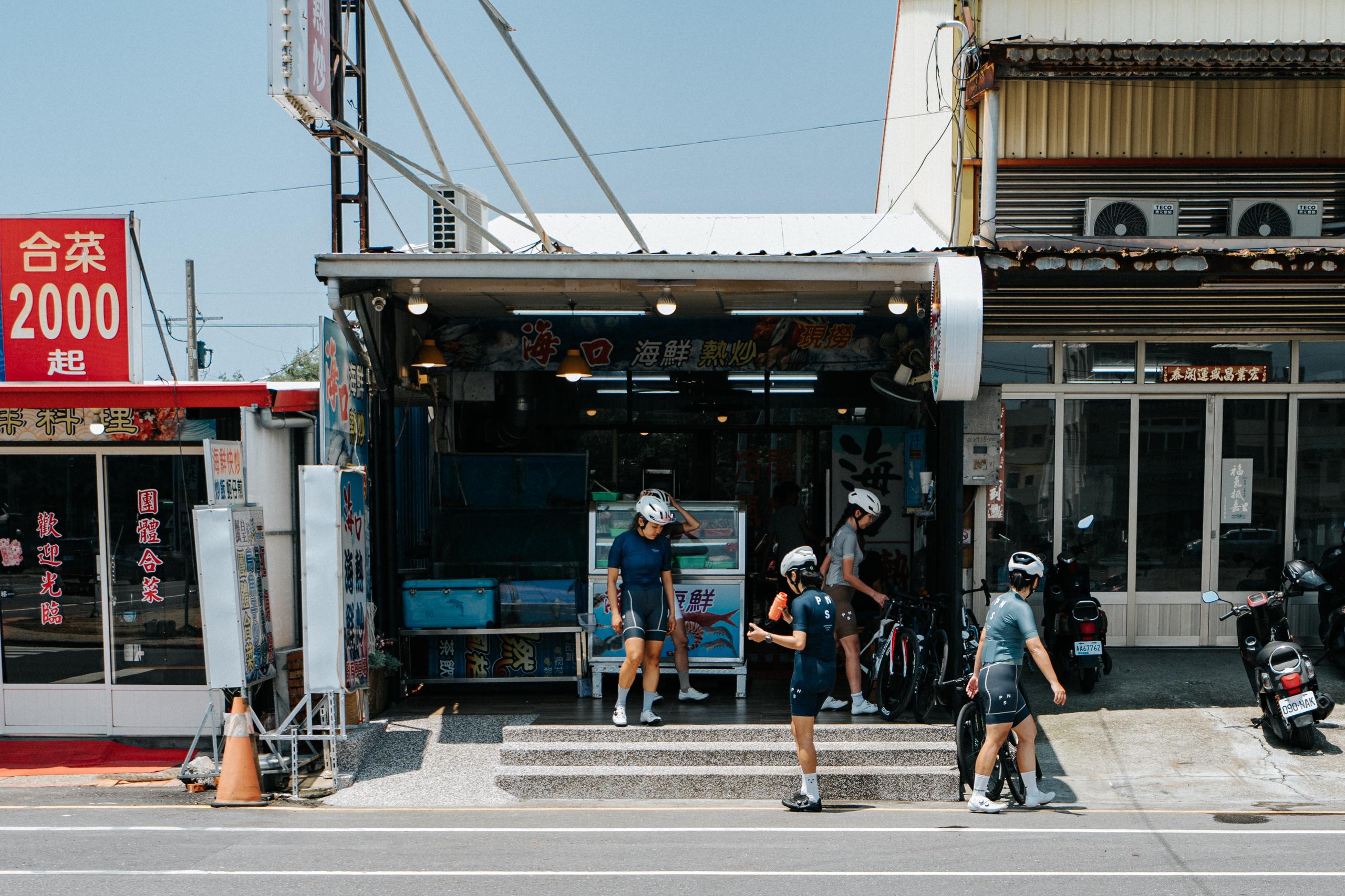 Cyclists in helmets and cycling apparel stopping at local seafood shop in Taiwan