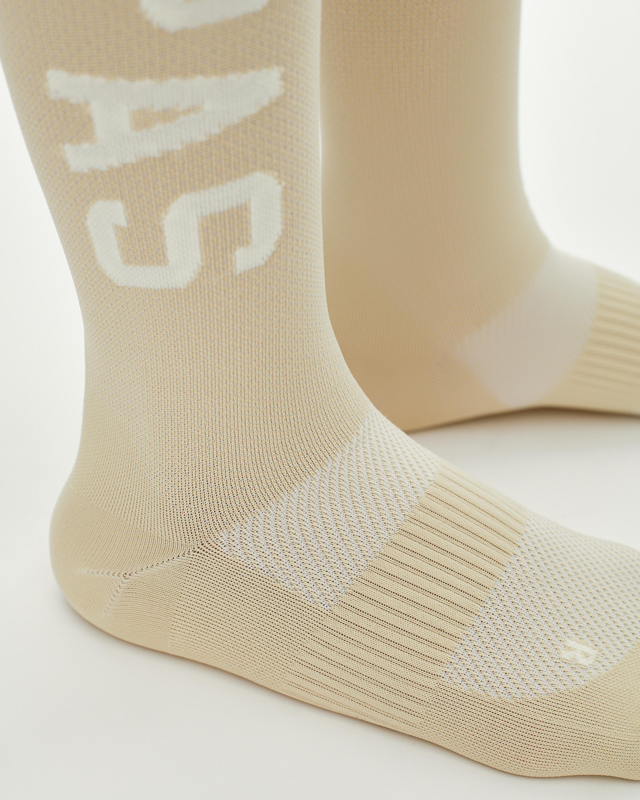 Cream PAS Race cycling socks, side view with white logo and ribbed cuff