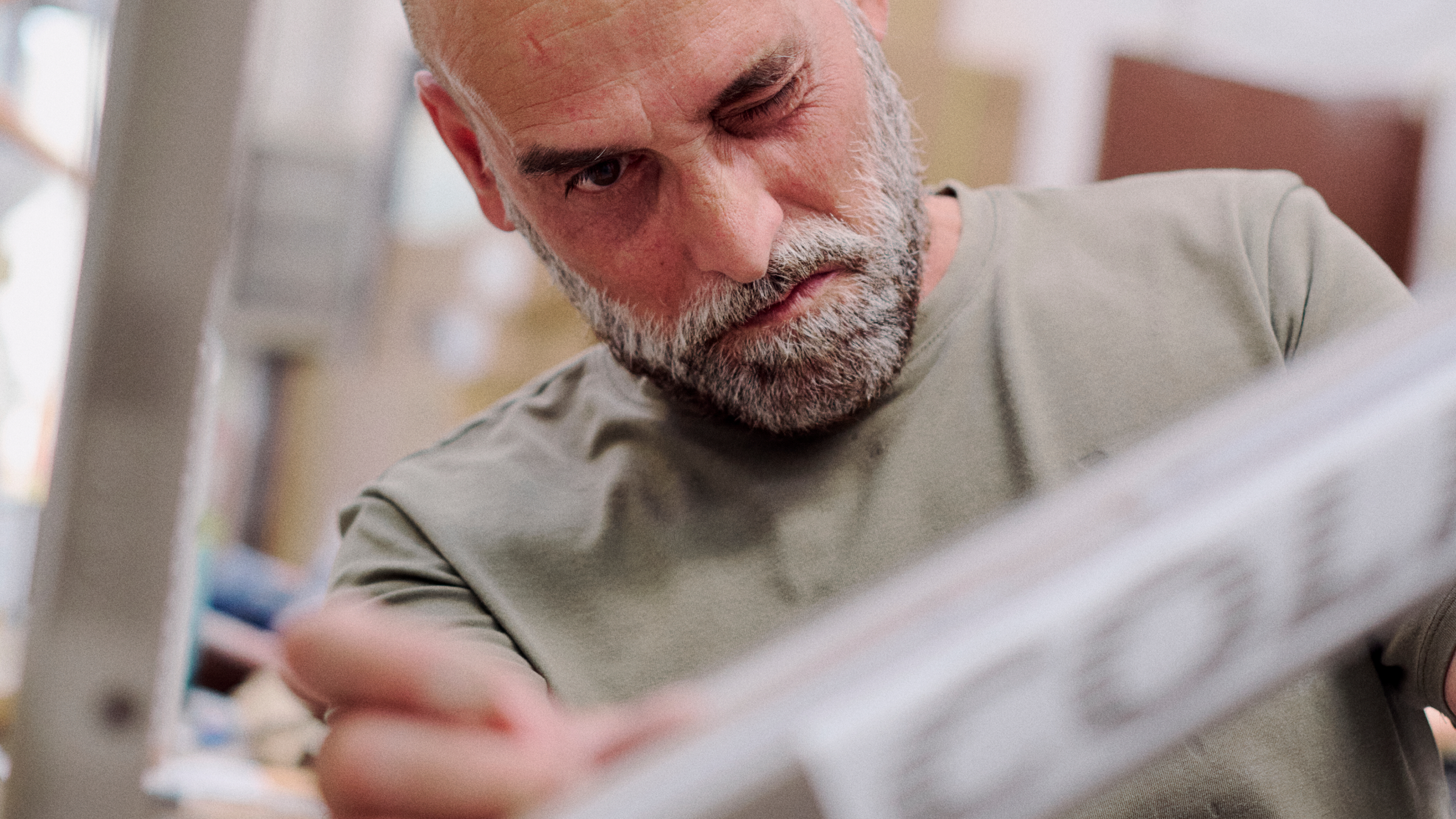 Model wearing beige long-sleeve shirt reading newspaper
