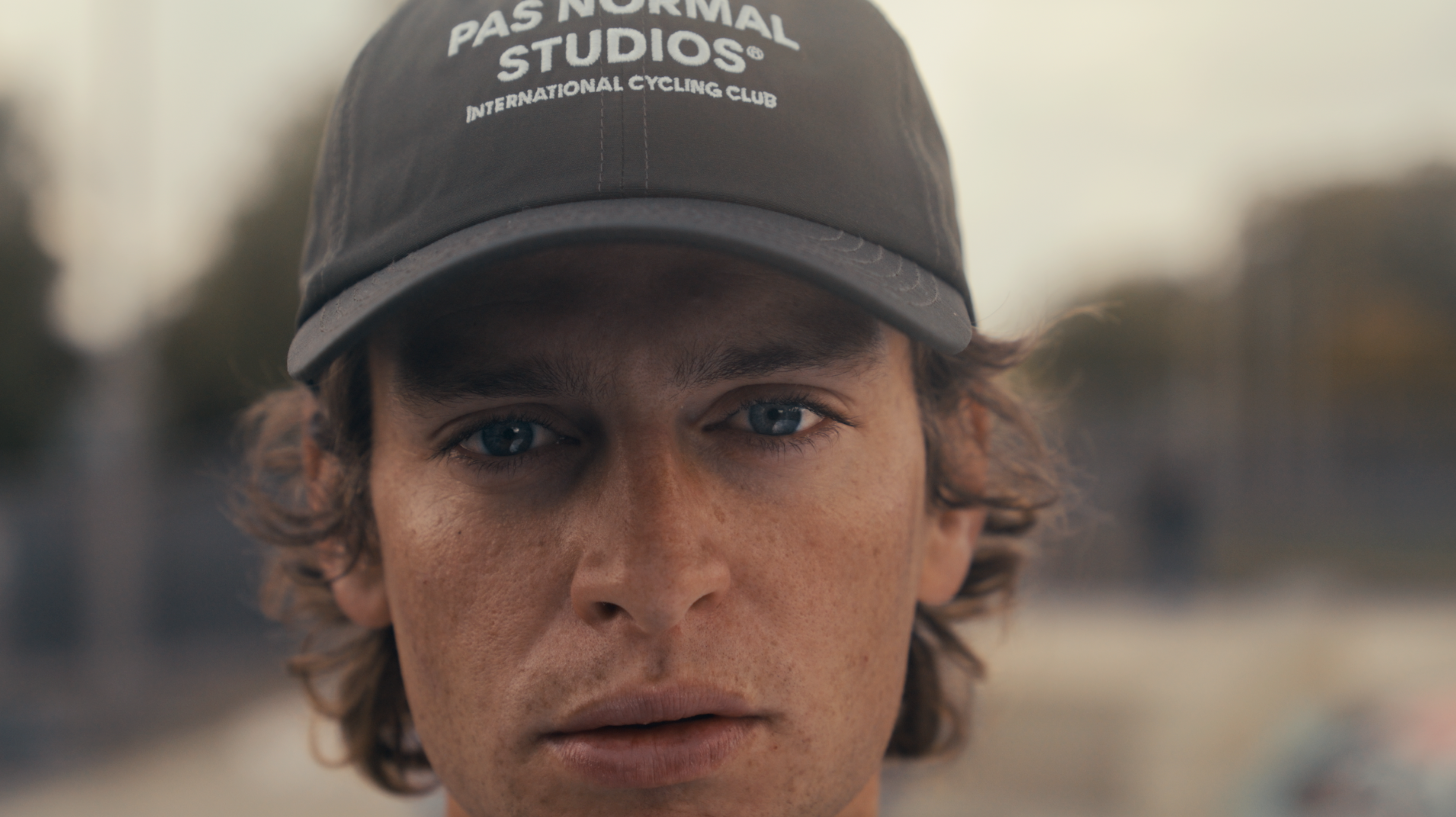 Model wearing dark grey cap with white branding and curved brim