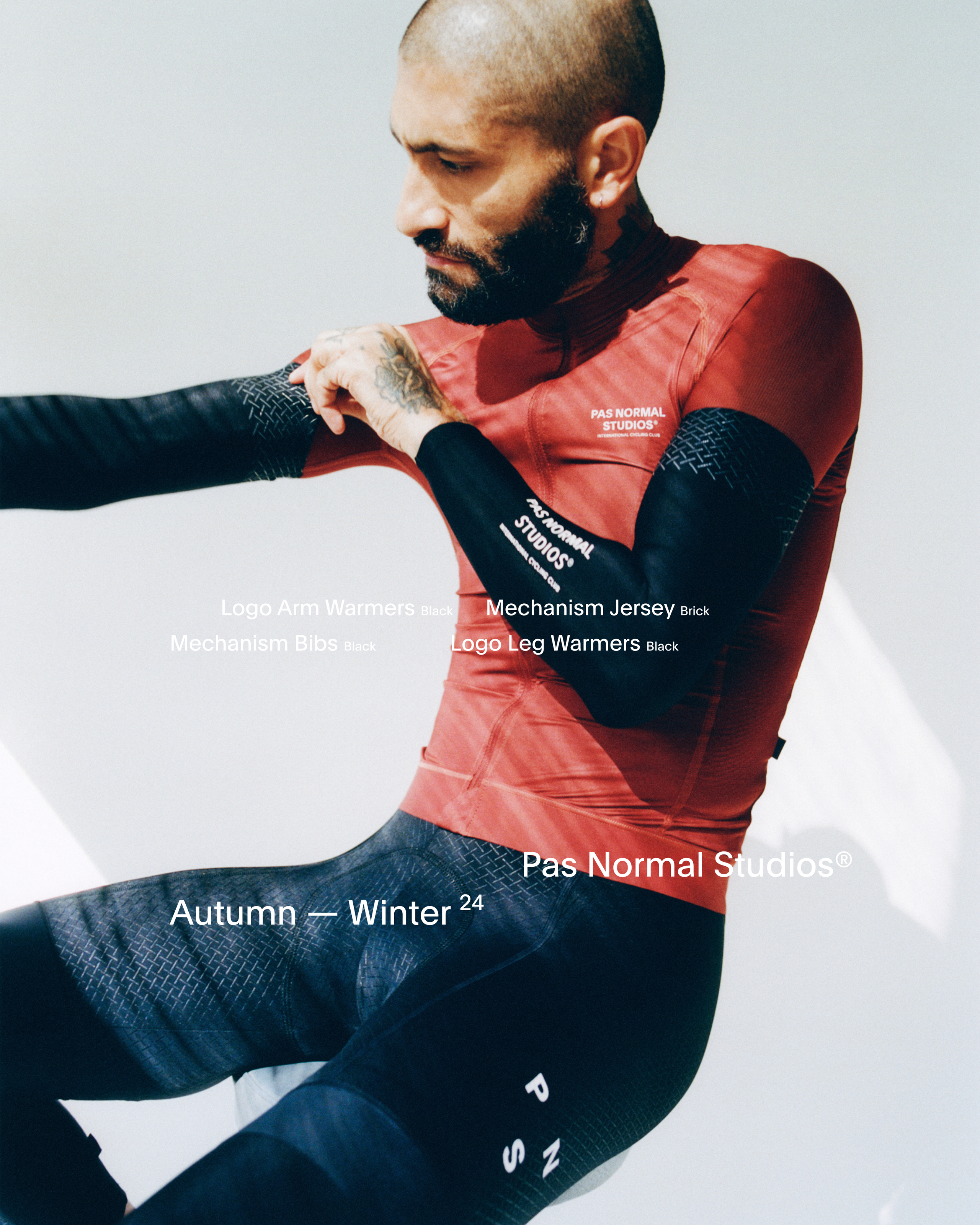 Model wearing Men's Mechanism Jersey in red with black Logo Arm Warmers and Logo Leg Warmers with geometric pattern