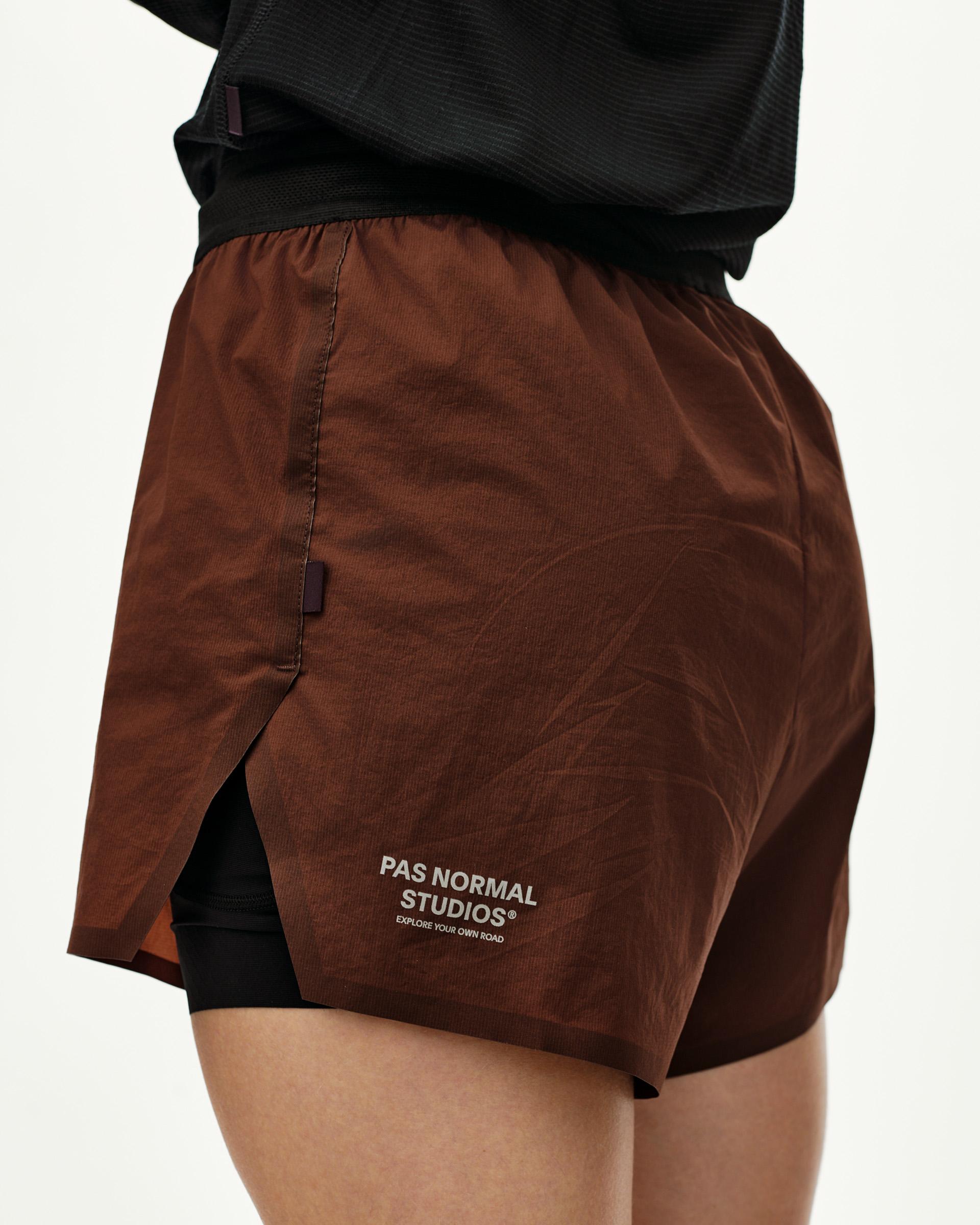 Maroon Brown Balance 2-in-1 shorts on model, three-quarter rear view with side split and black inner layer