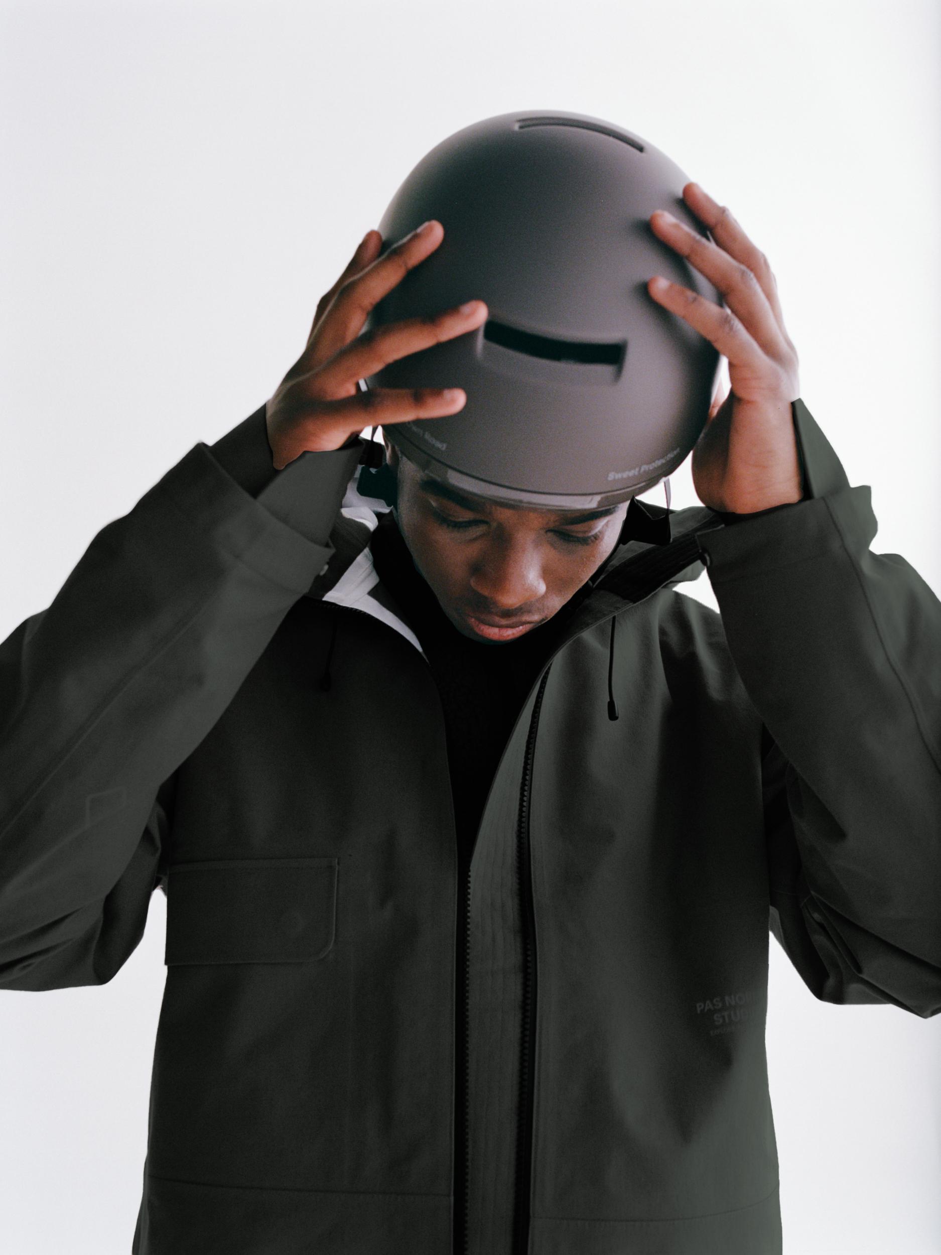 Brown Commuter Mips cycling helmet on model adjusting fit with both hands