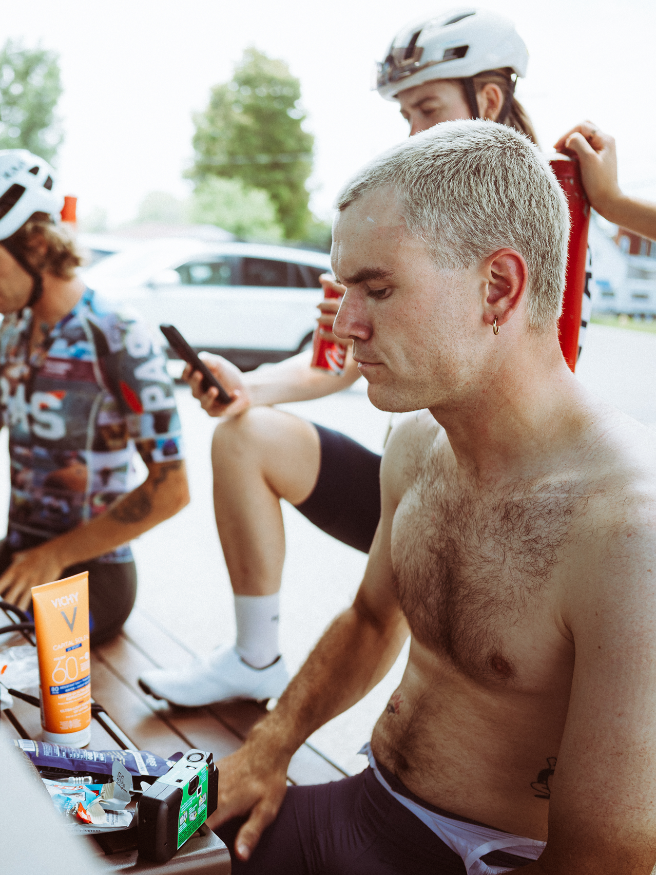 Cyclists taking a break during Montreal to Quebec ride, applying sunscreen and checking phones