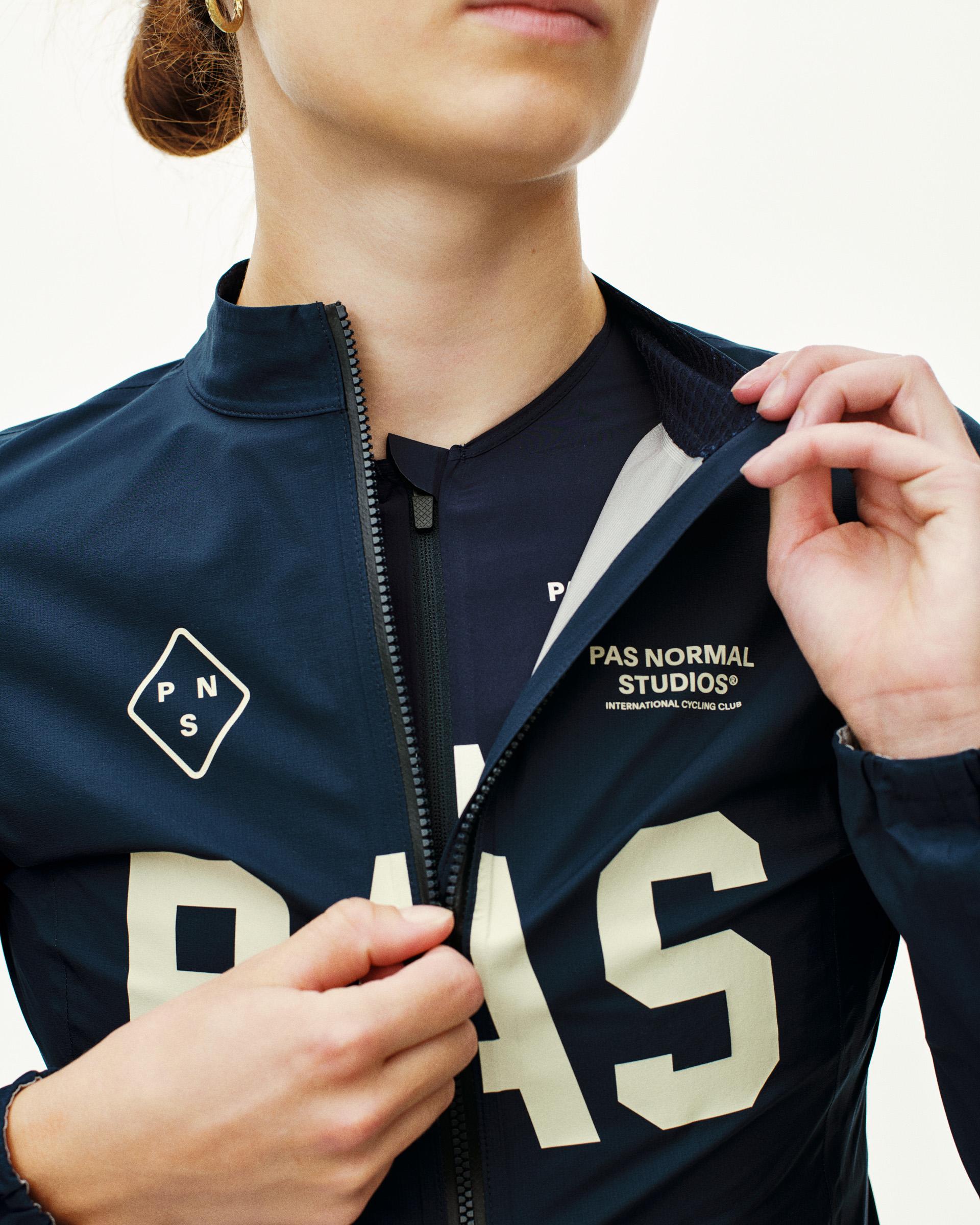 Navy PAS Mechanism Rain cycling jacket on model with white PAS lettering and contrast zip
