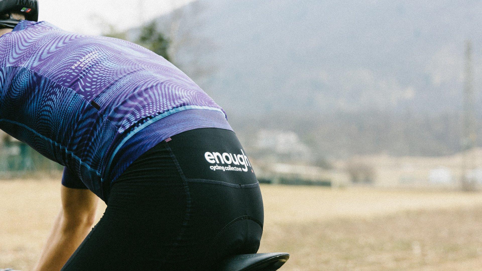 Model wearing purple geometric patterned jersey with black shorts, cycling outdoors