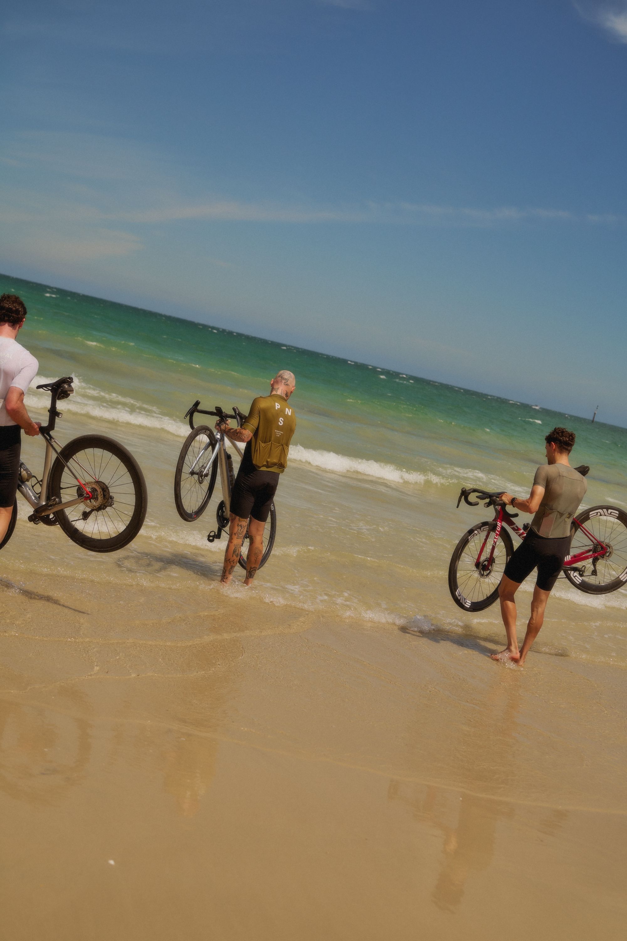 Cyclists with bikes on beach, ocean waves in background