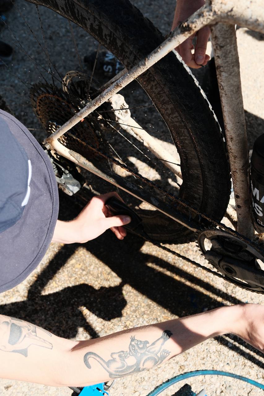 Cyclist repairing muddy bike wheel on gravel surface