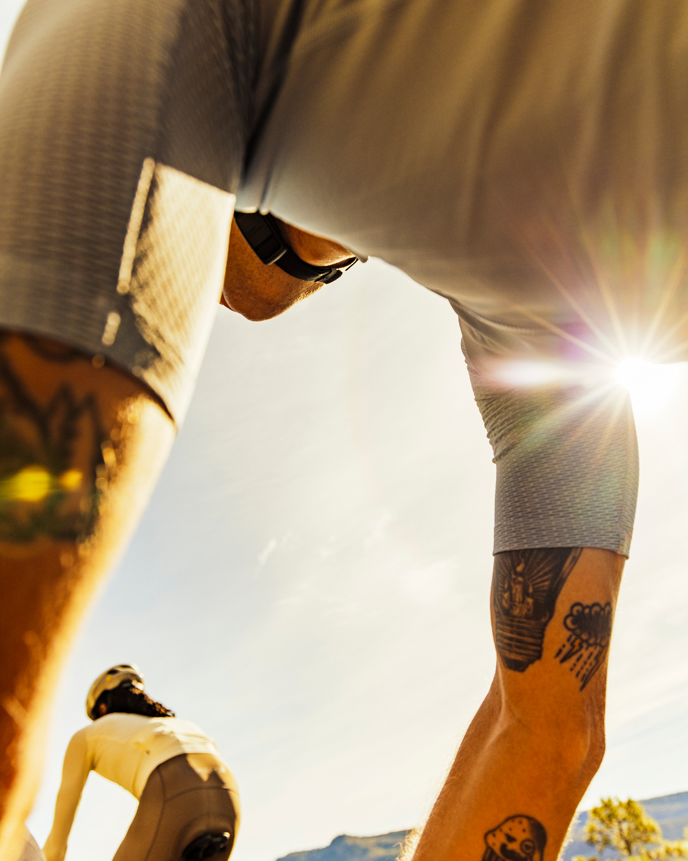 Model wearing white Essential Light sleeveless jersey with sunglasses cycling on sunny road