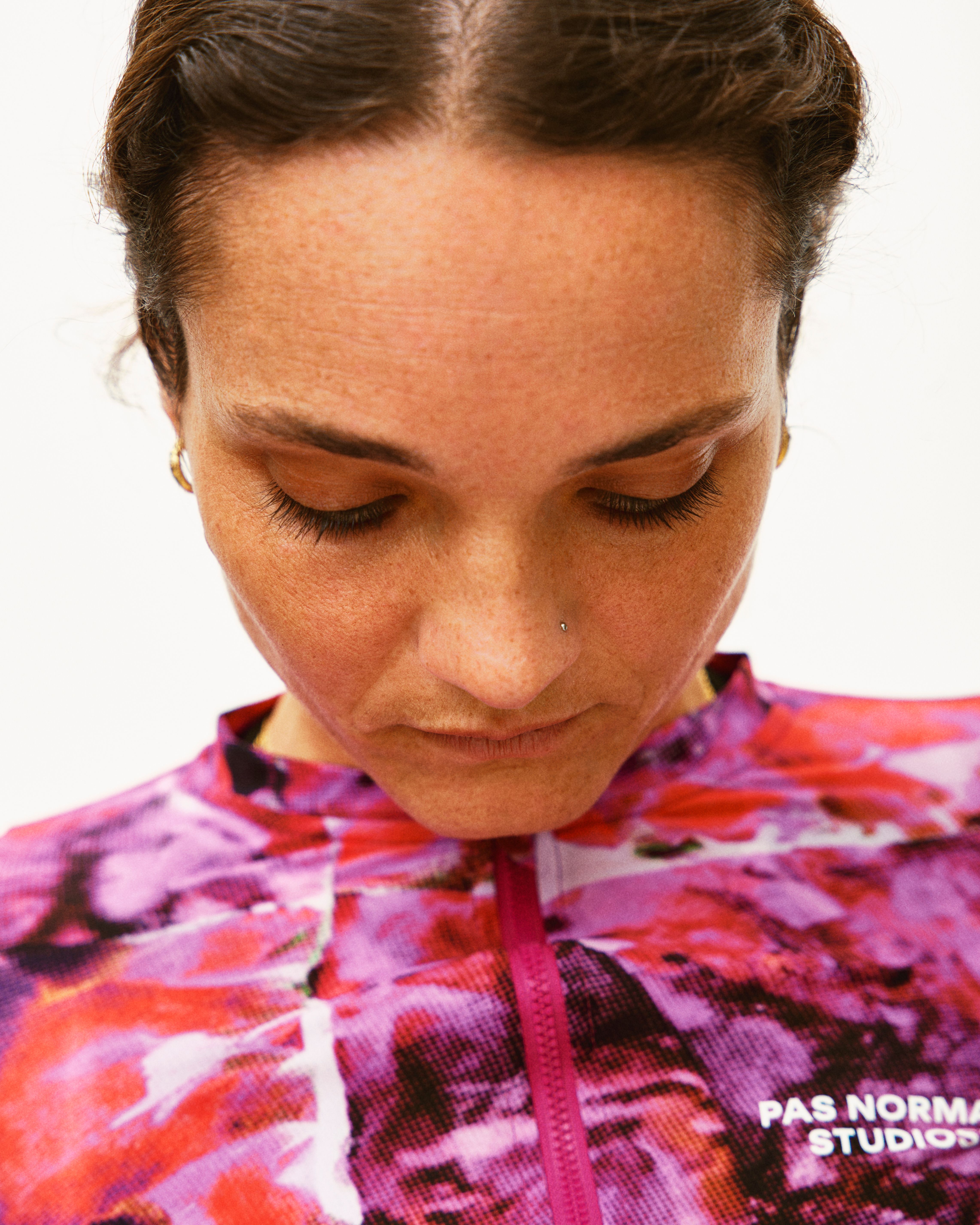 Model wearing Women's Essential cycling jersey in pink and red abstract pattern with quarter zip