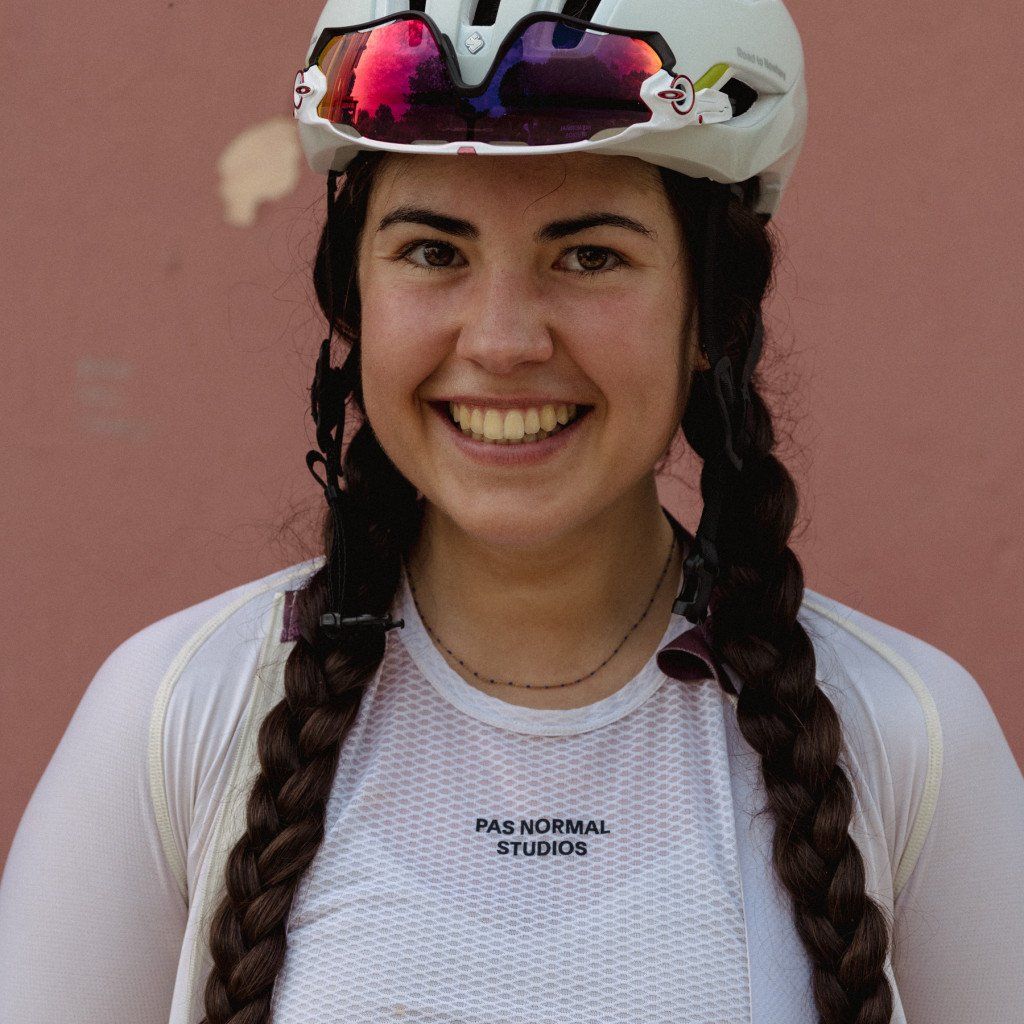Model wearing white mesh cycling jersey with colorful mirrored sunglasses and white helmet