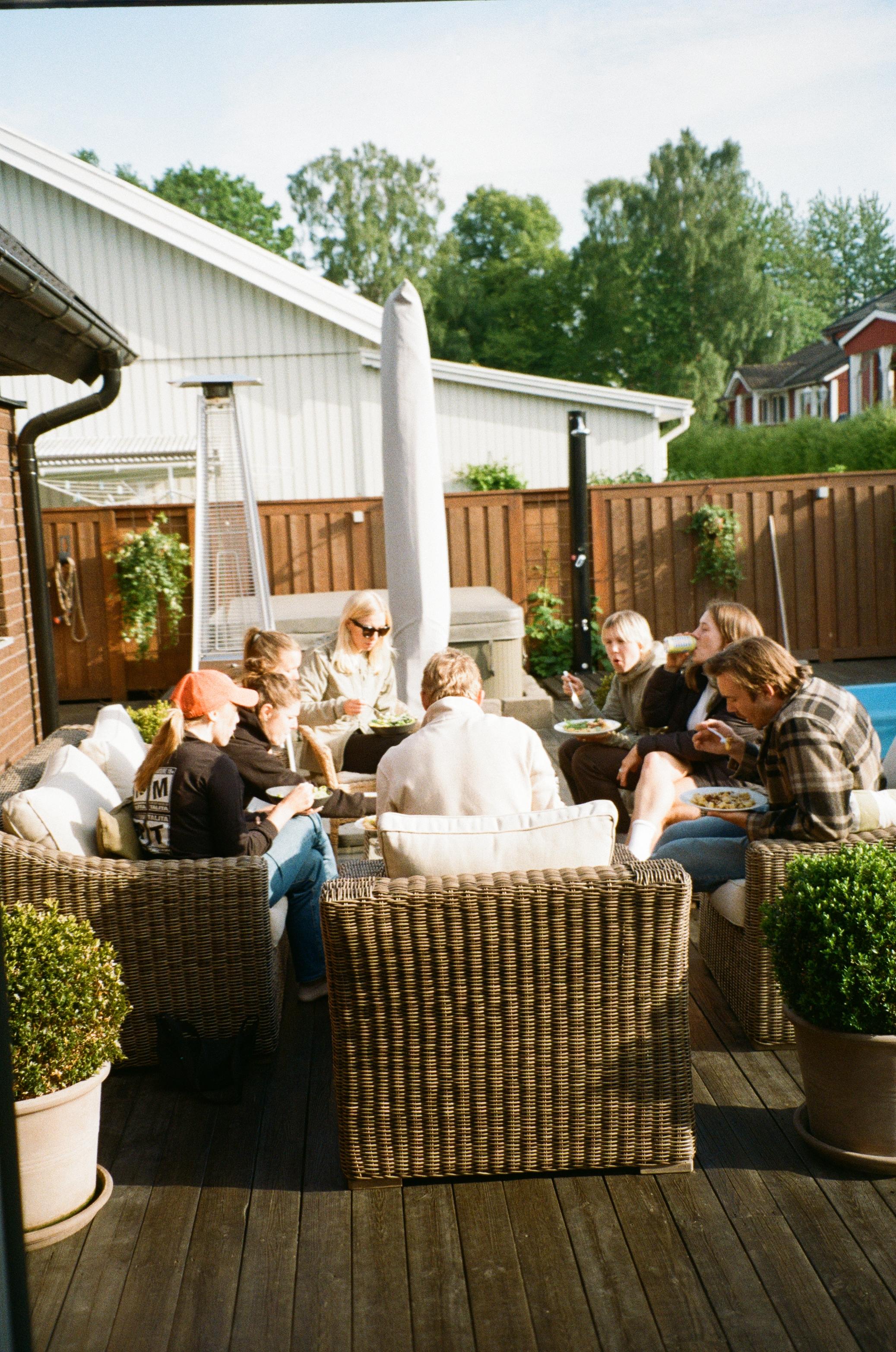 Group of cyclists relaxing on outdoor patio with wicker furniture after completing Vätternrundan race