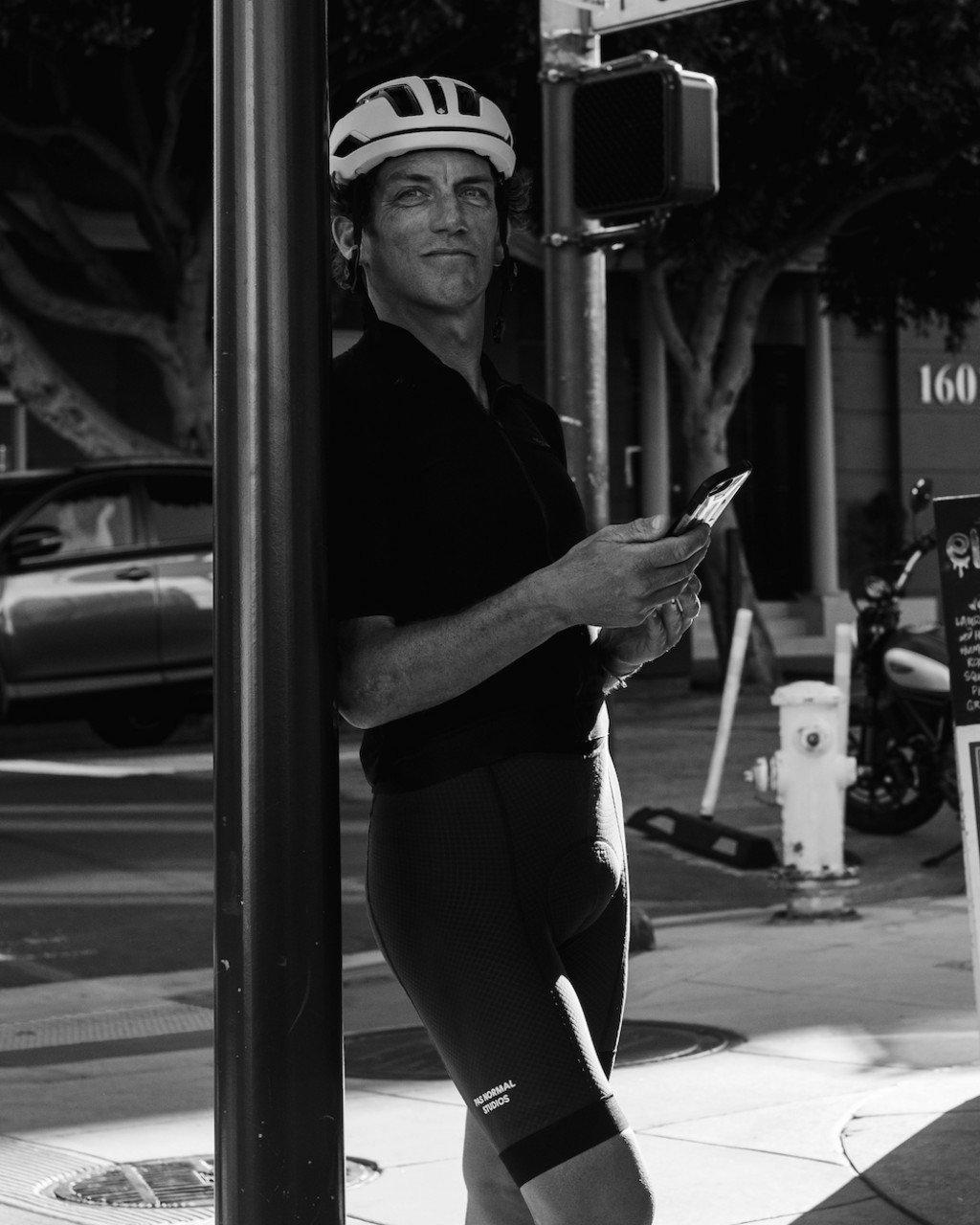 Model wearing black cycling jersey and shorts with helmet on urban street in black and white