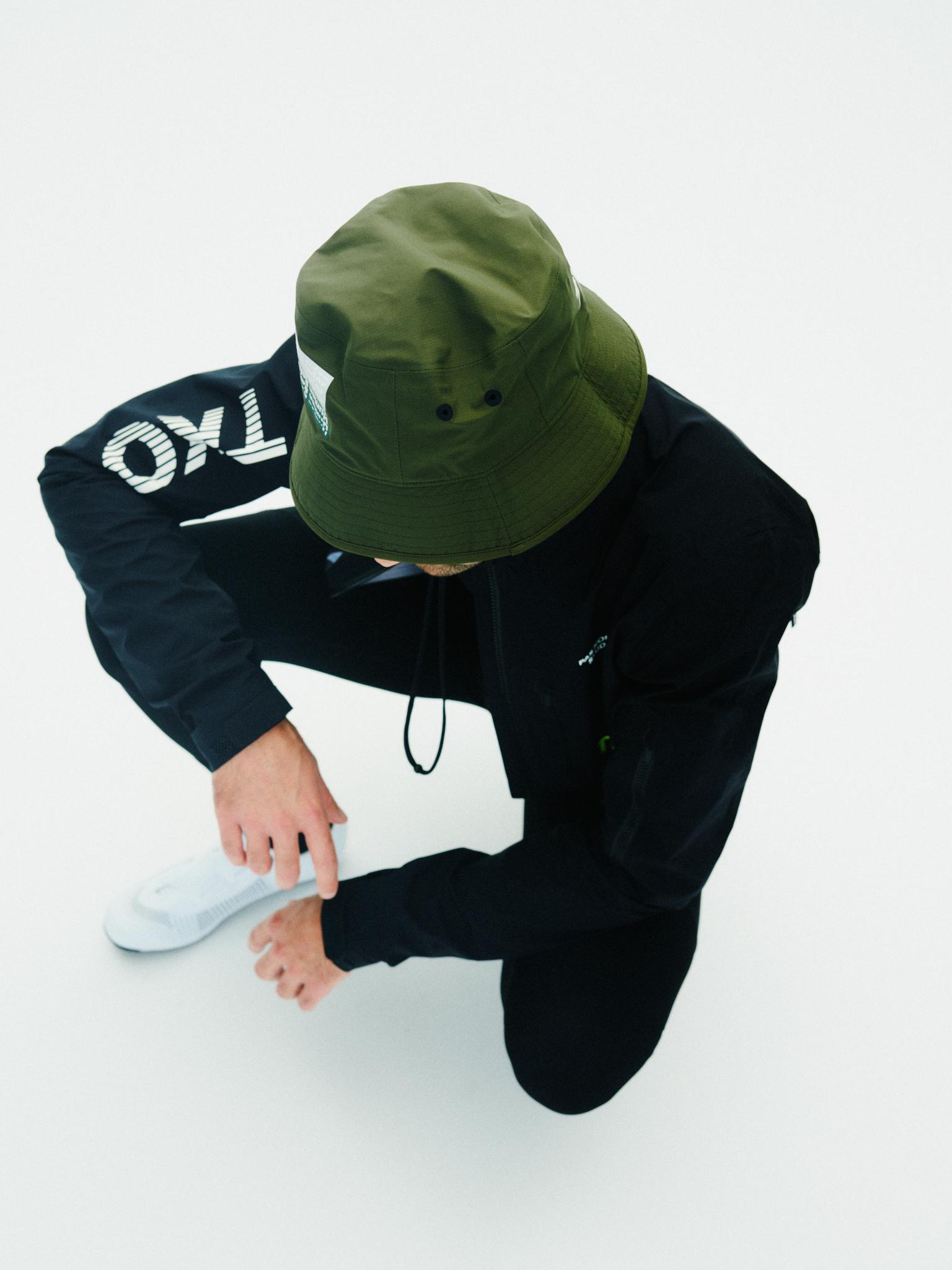 Olive T.K.O. Off-Race Shield bucket hat on model, overhead view with label tab on brim