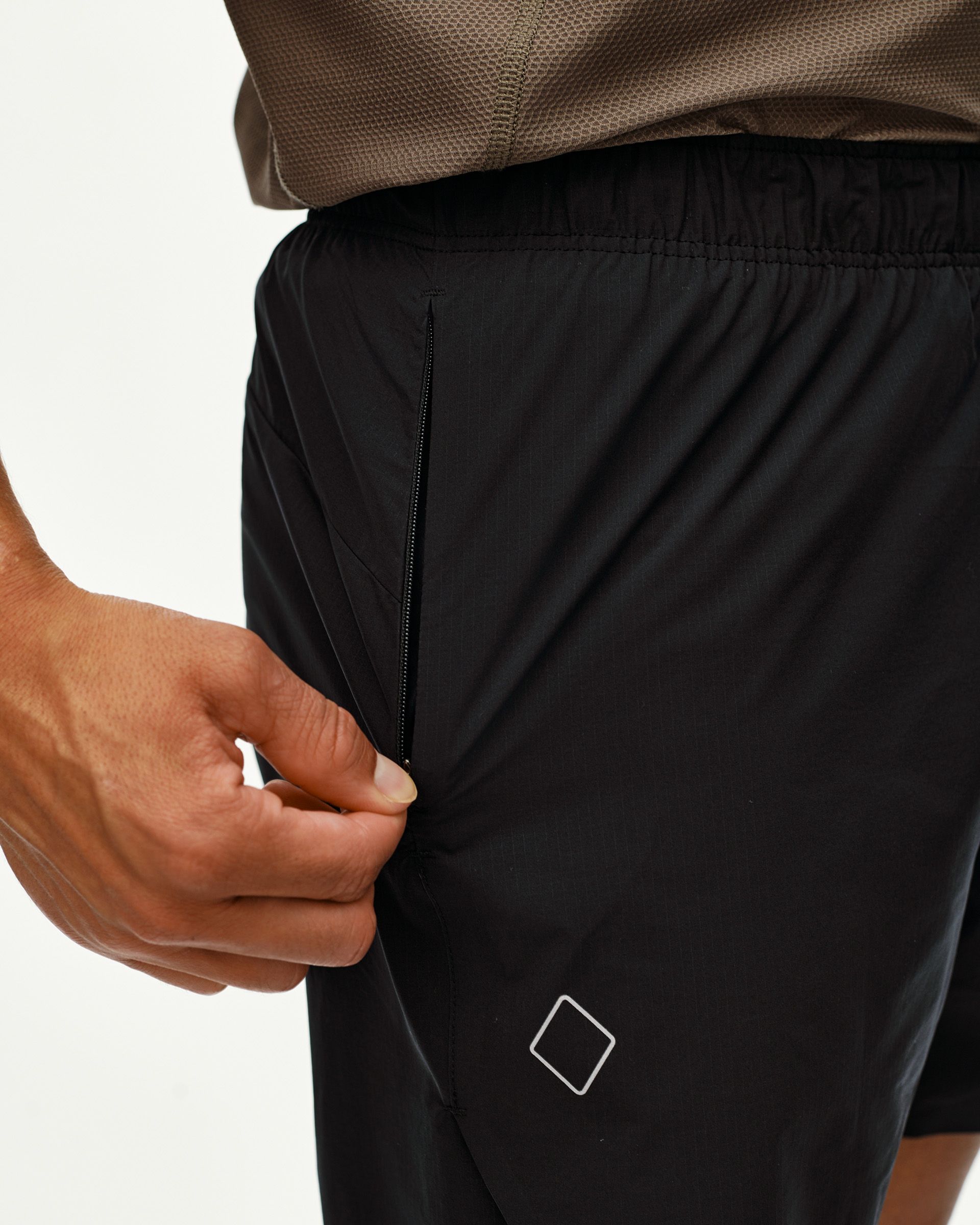 Black Balance shorts on model, detail view of zip side pocket with diamond logo patch