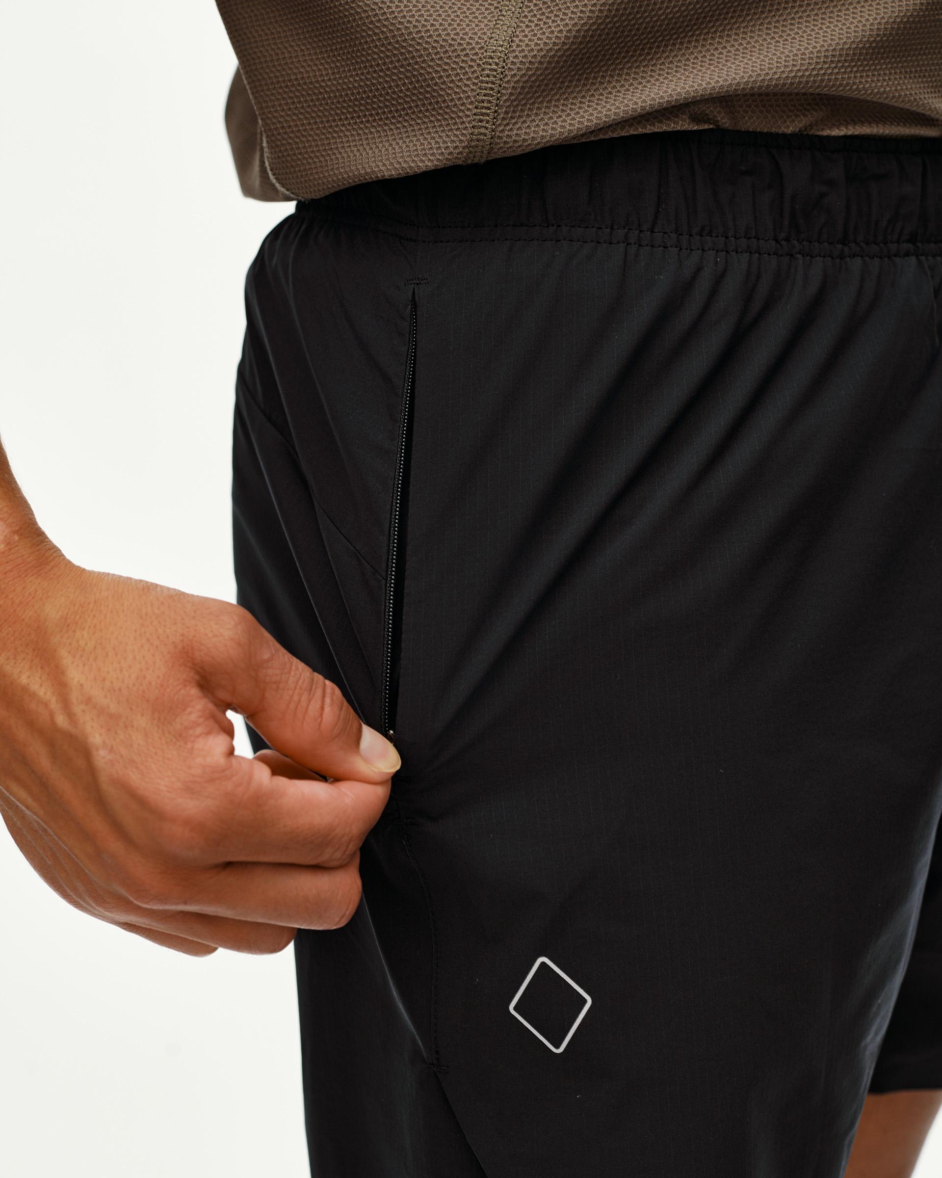 Black Balance shorts on model, detail view of zip side pocket with diamond logo patch