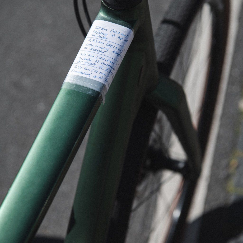 Green bicycle frame with white label containing handwritten notes