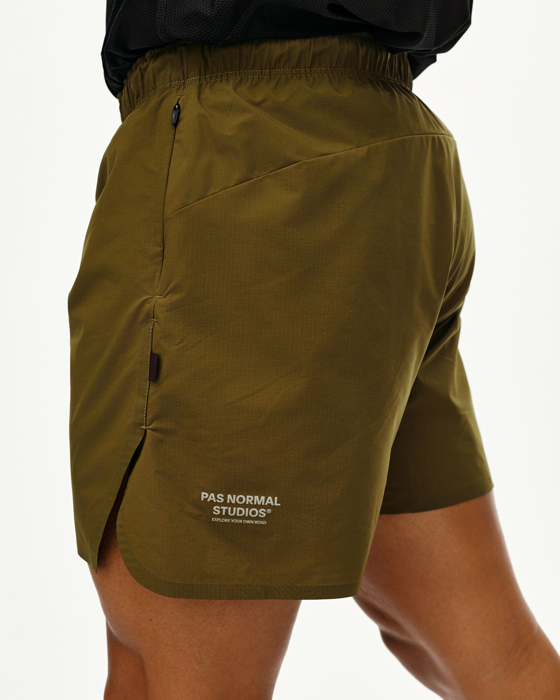 Moss Brown Balance shorts on model, side view with zip hip pocket and side vent