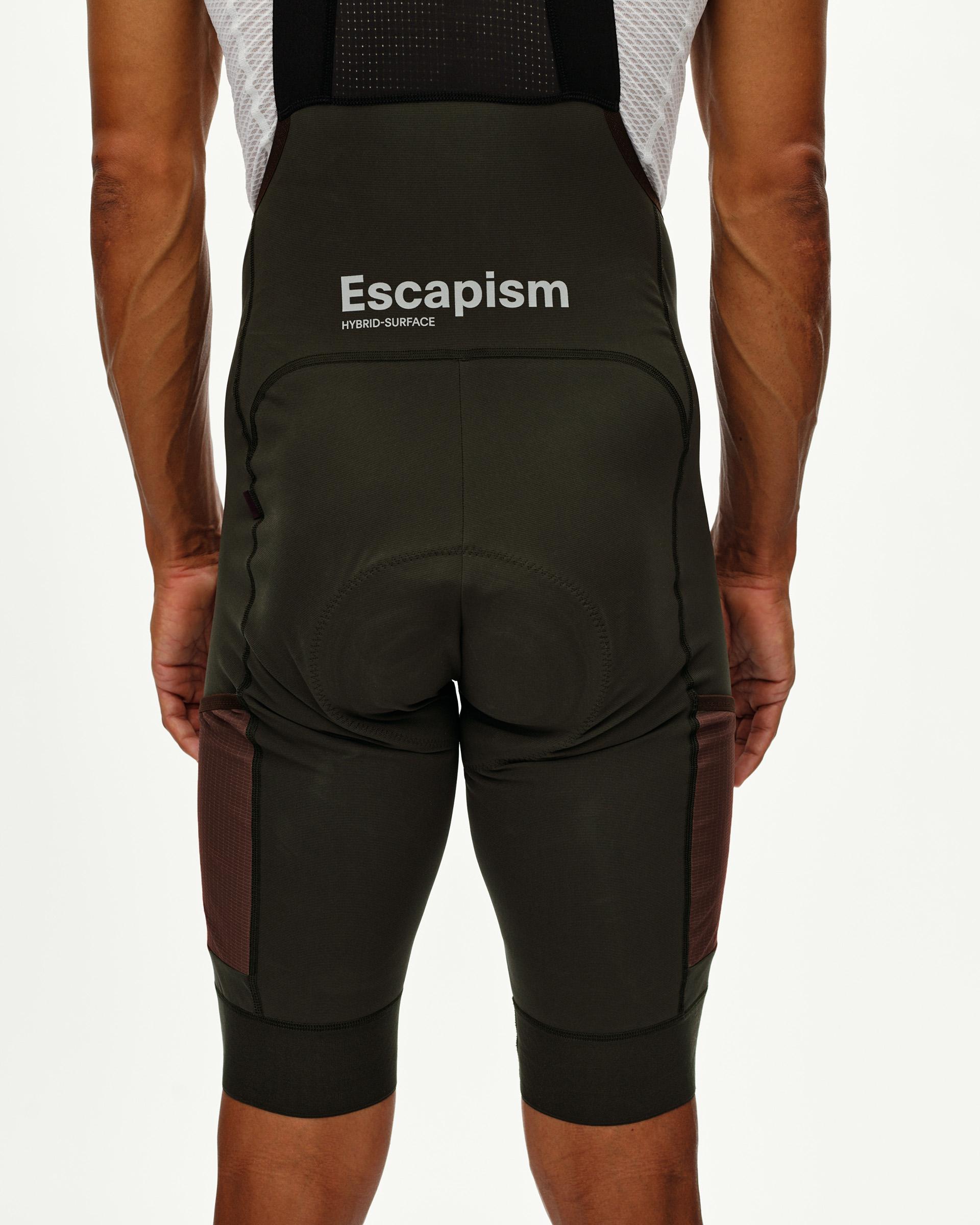 Dark Olive Escapism Cargo cycling bibs on model, rear view with contrast side cargo pockets and back text print