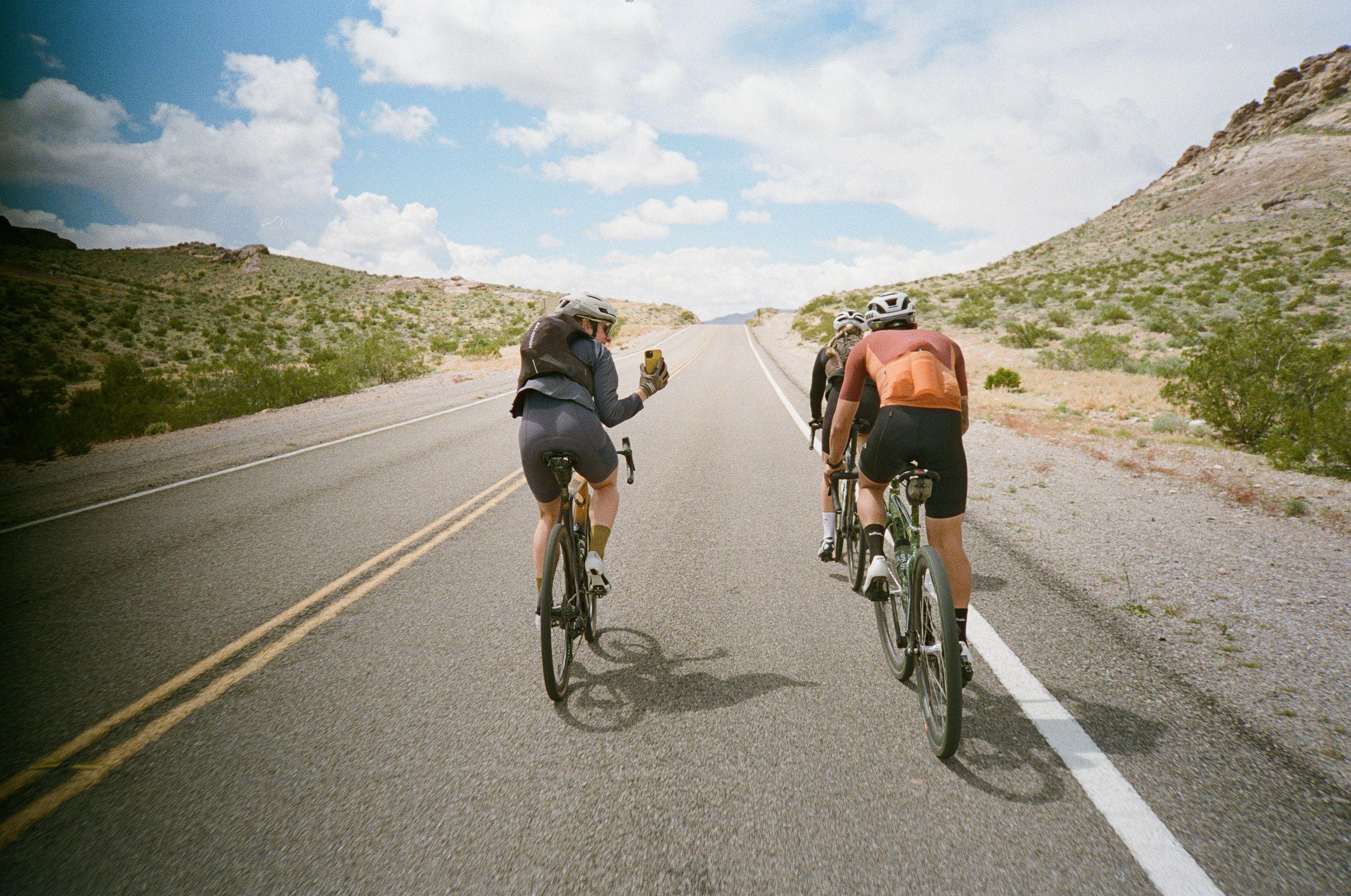 Cyclists riding on desert road through Death Valley in cycling apparel