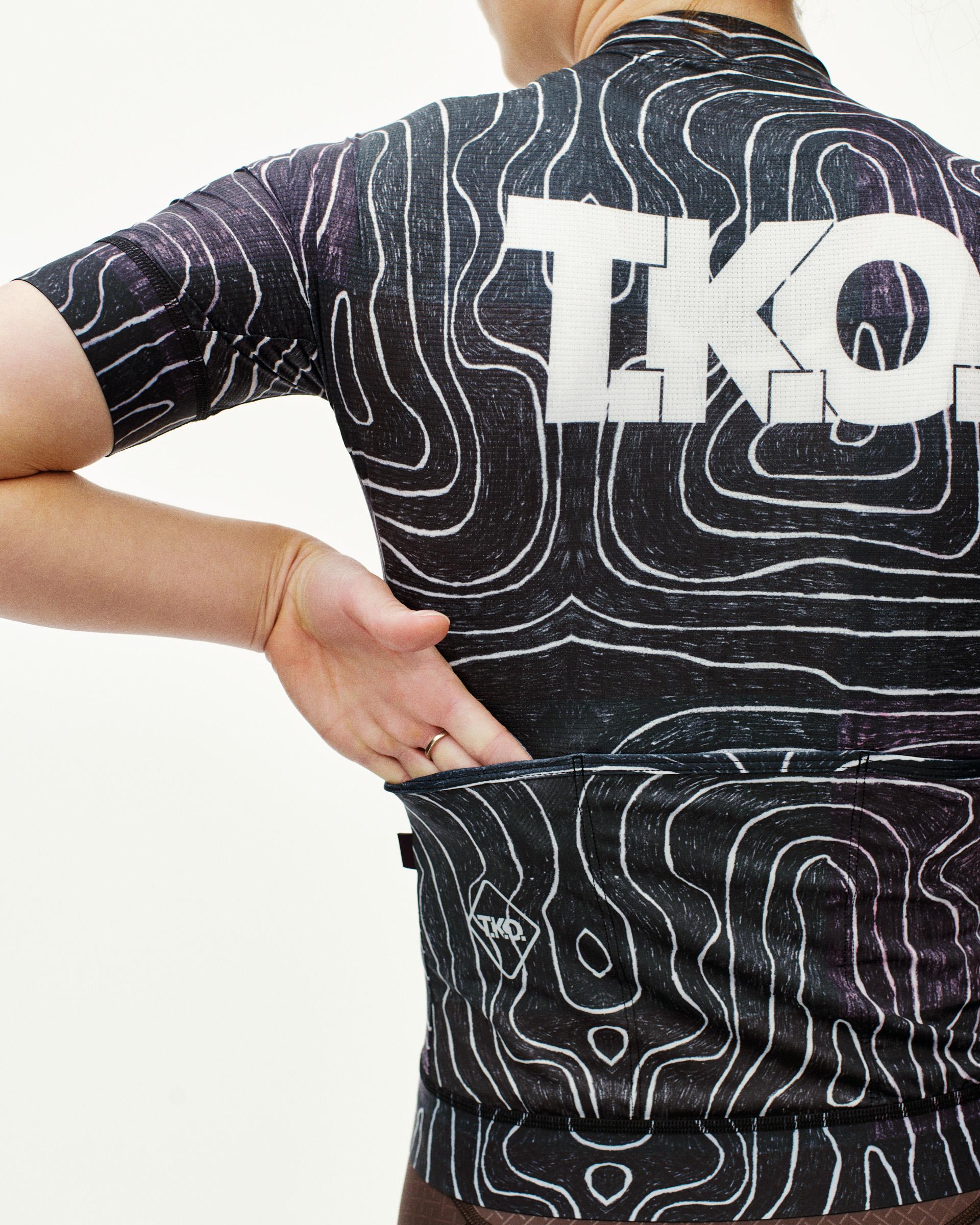 Black Multi T.K.O. Mechanism women's cycling jersey, rear view on model showing topographic print and back pockets