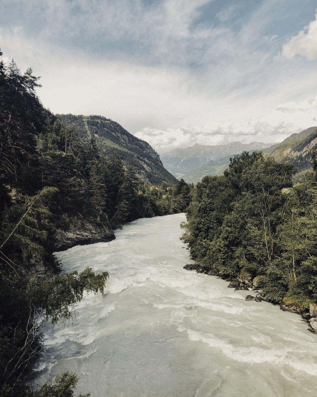 Mountain river flowing through forested valley with peaks in distance