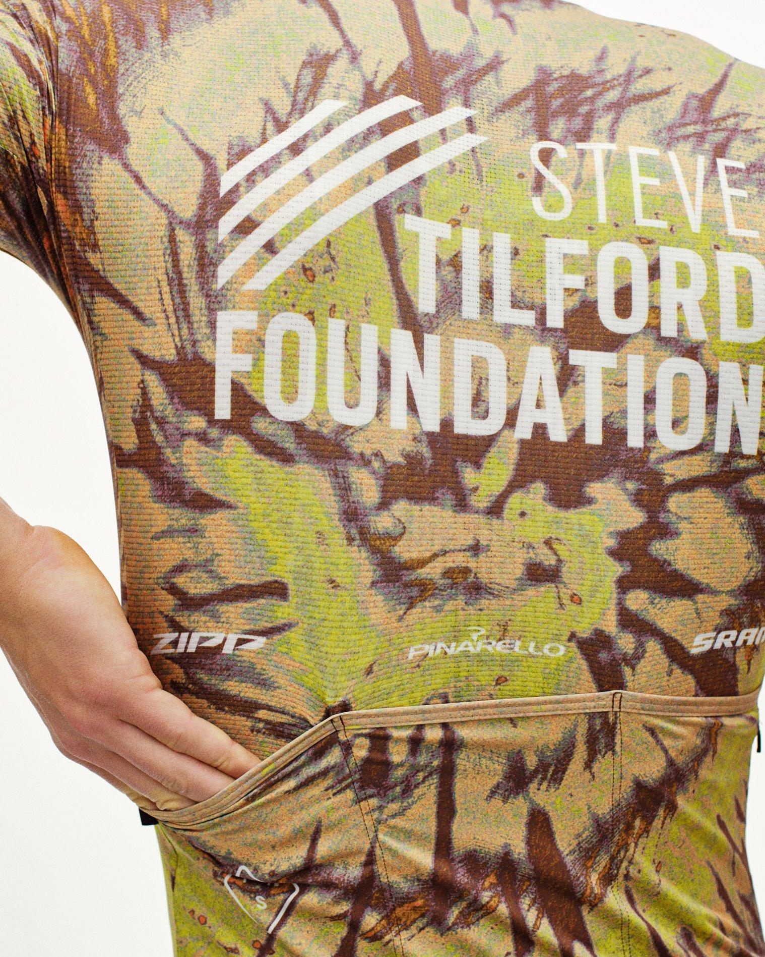 Beige STFR Mechanism long sleeve speedsuit on model with camouflage print and white chest logo