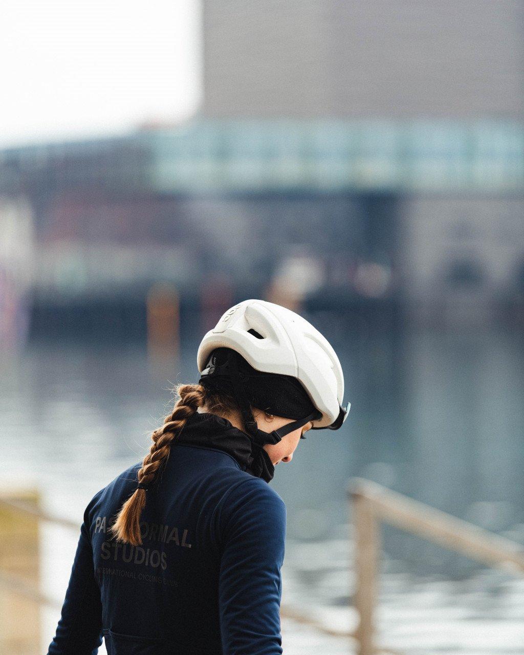 Model wearing white cycling helmet and navy long sleeve jersey with back branding