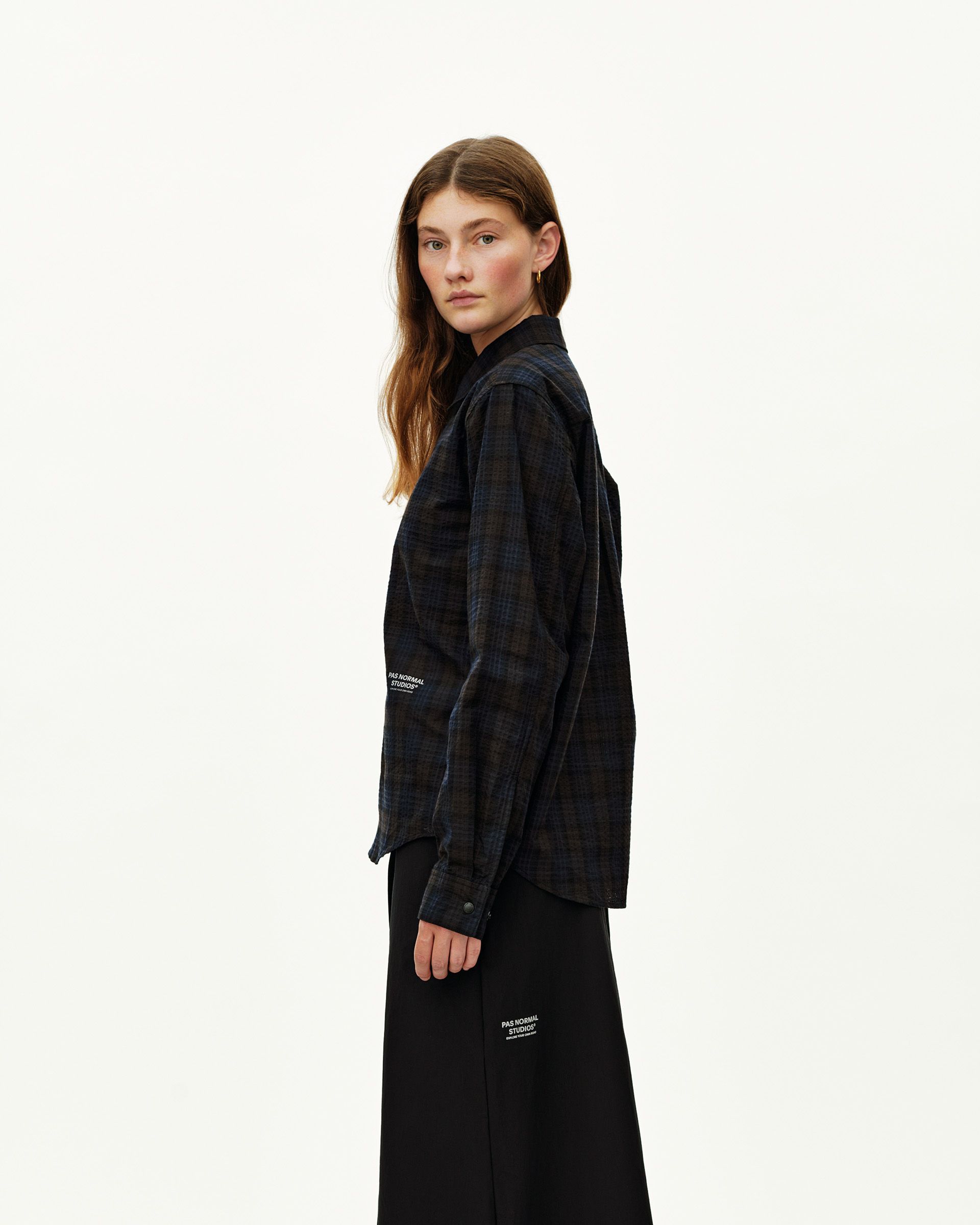 Dark Navy Off-Race Seersucker shirt on model, side view with dark plaid pattern and white logo print at hem