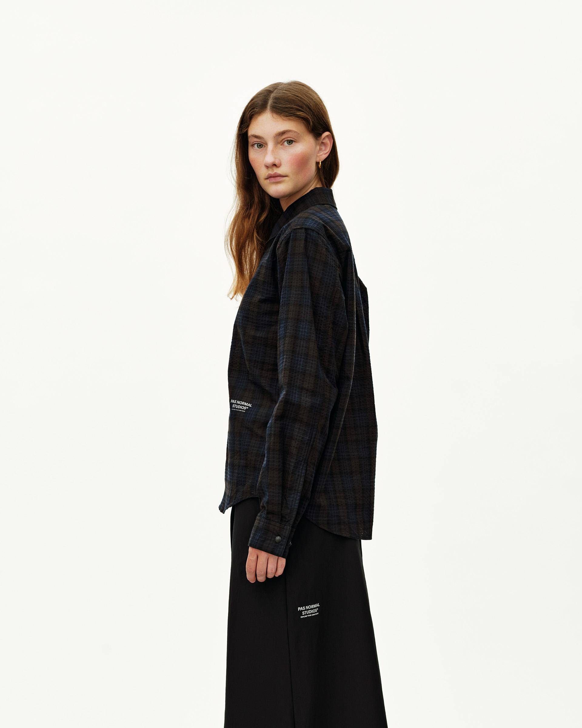 Dark Navy Off-Race Seersucker shirt on model, side view with dark plaid pattern and white logo print at hem