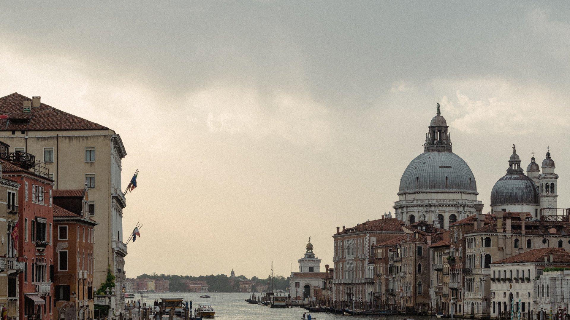 Venice canal view with historic buildings and domed basilica under overcast sky