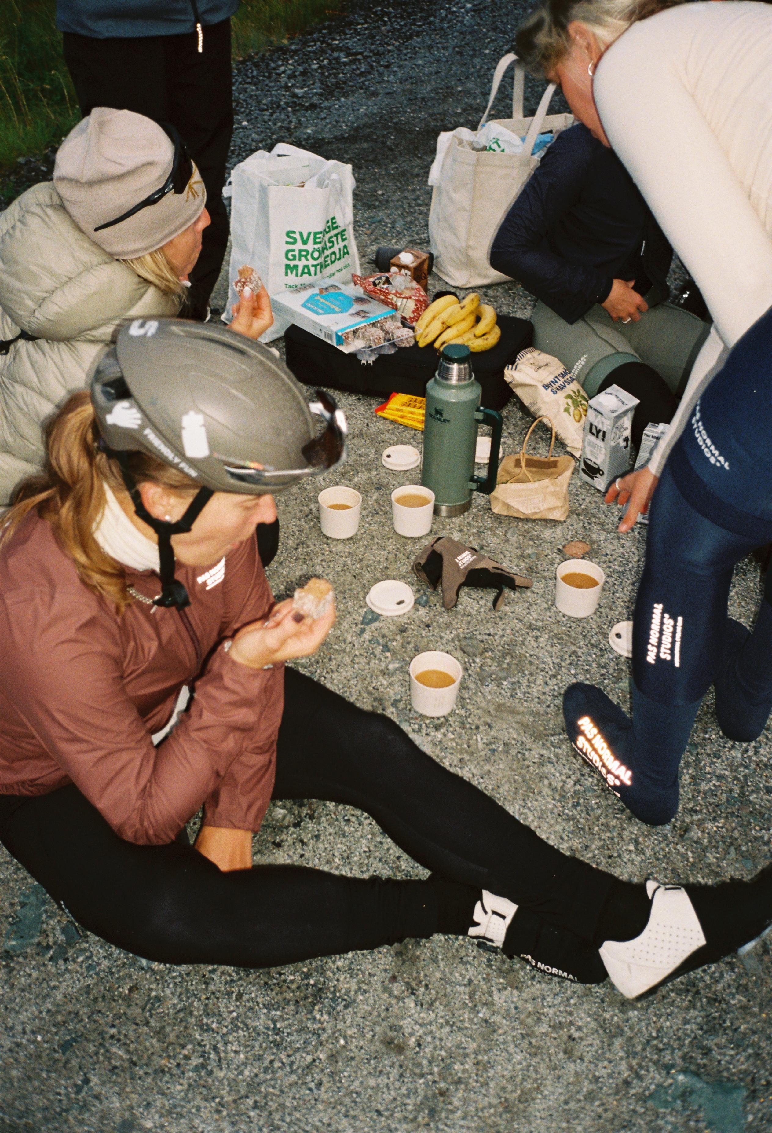 Models wearing cycling apparel sharing coffee and snacks during outdoor cycling break