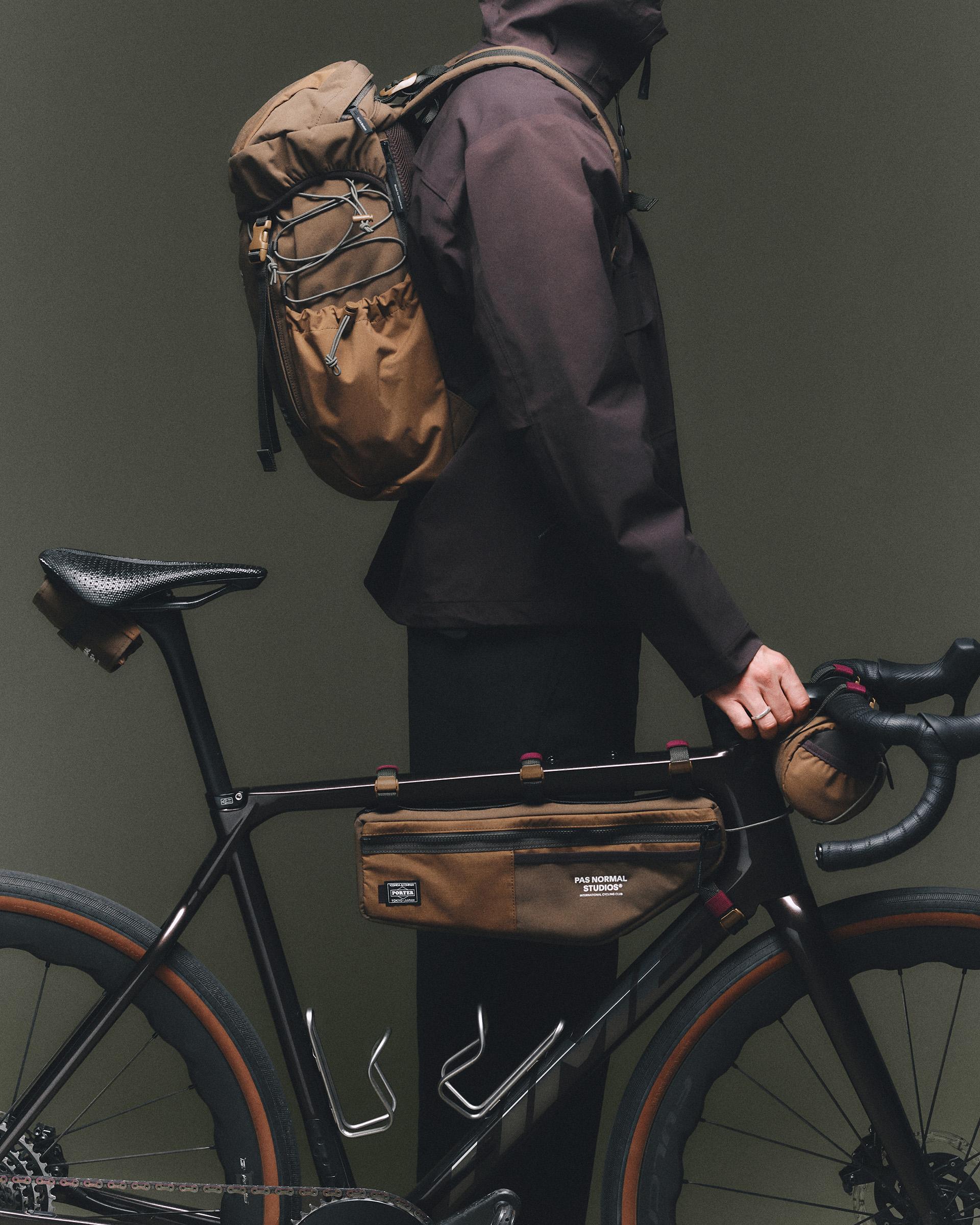 Light Brown Porter-Yoshida frame bag on model with matching backpack, side view with zip closure and branded label