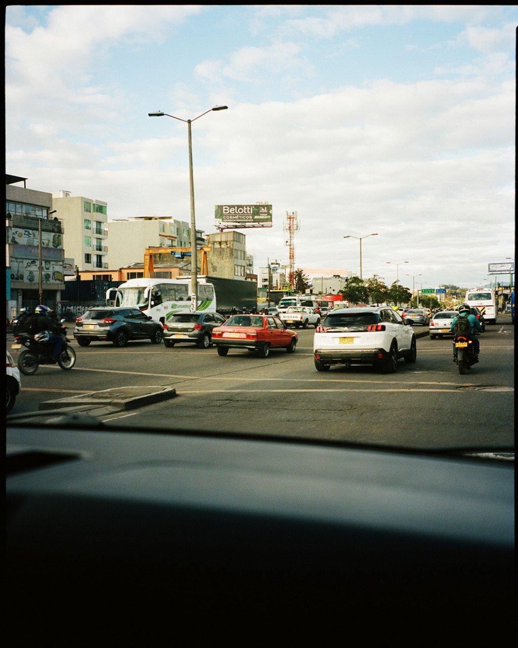 Busy street scene with cars and motorcycles viewed from inside a vehicle in urban setting