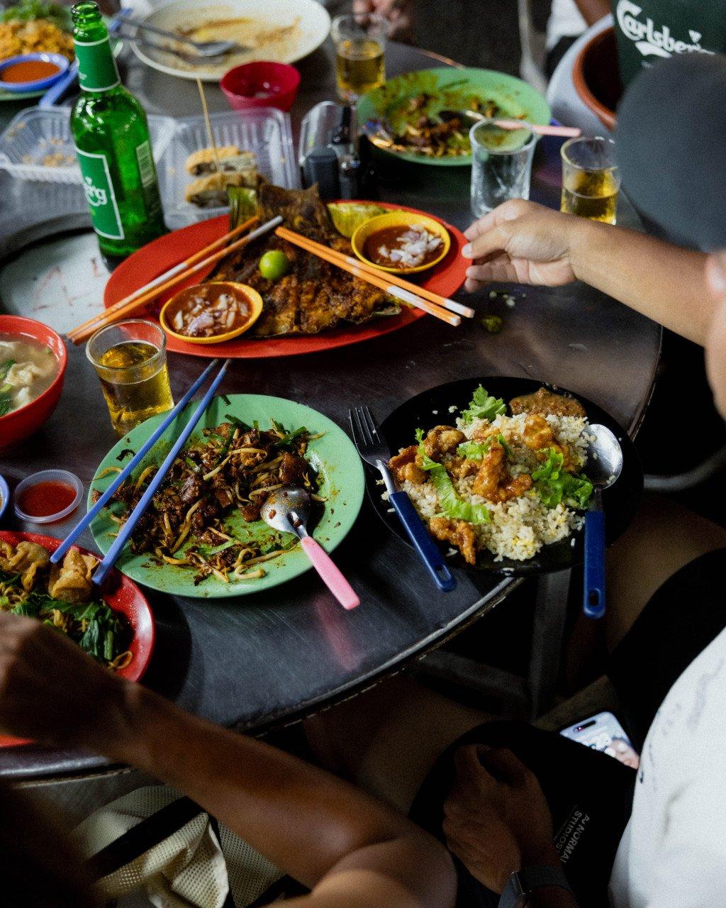 Person dining at table with traditional Asian dishes and beverages in Singapore