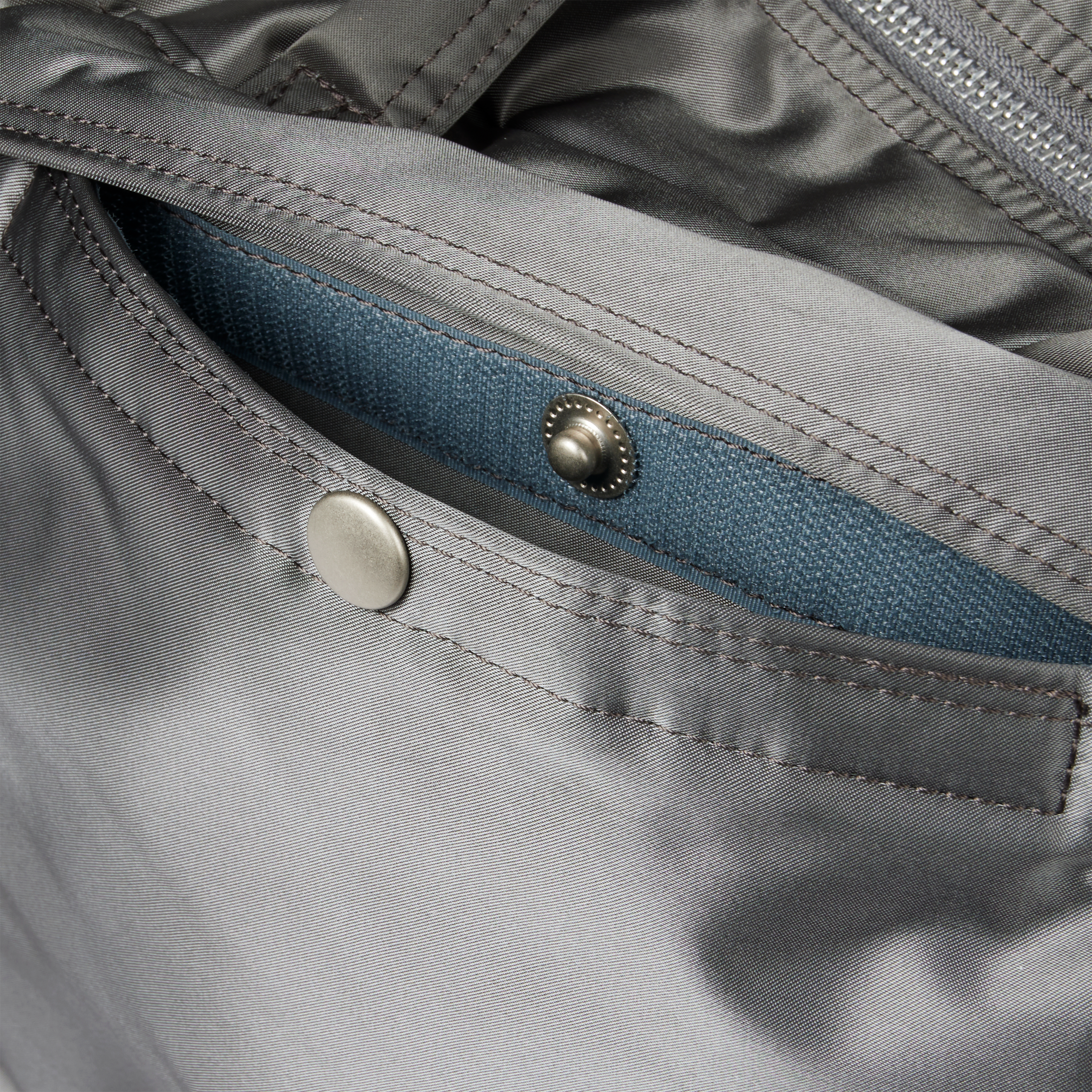 Grey Porter-Yoshida 2-Way briefcase, detail view showing blue interior pocket with metal snap closure
