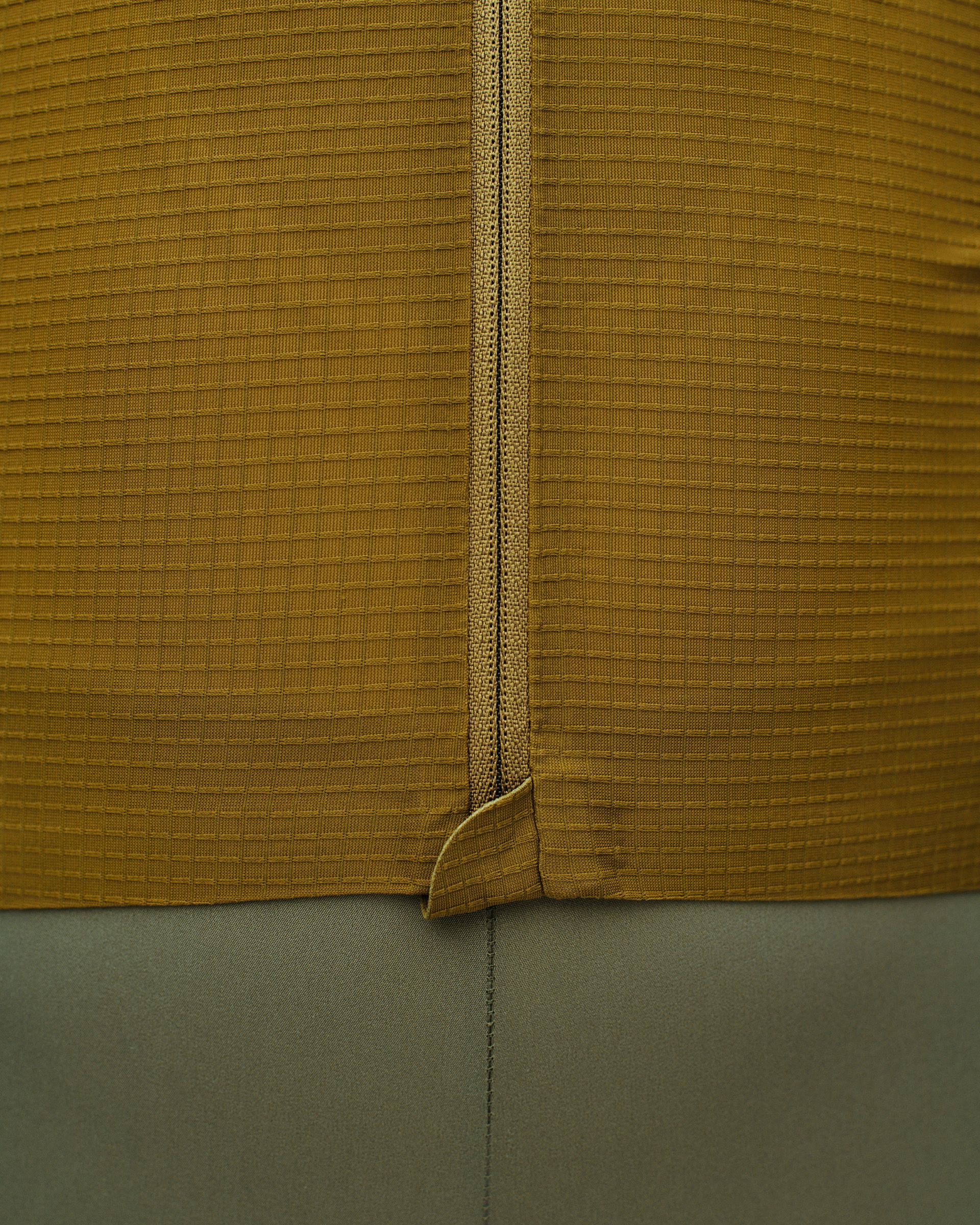 Close-up of mustard yellow ribbed fabric with central seam detail and green fabric below