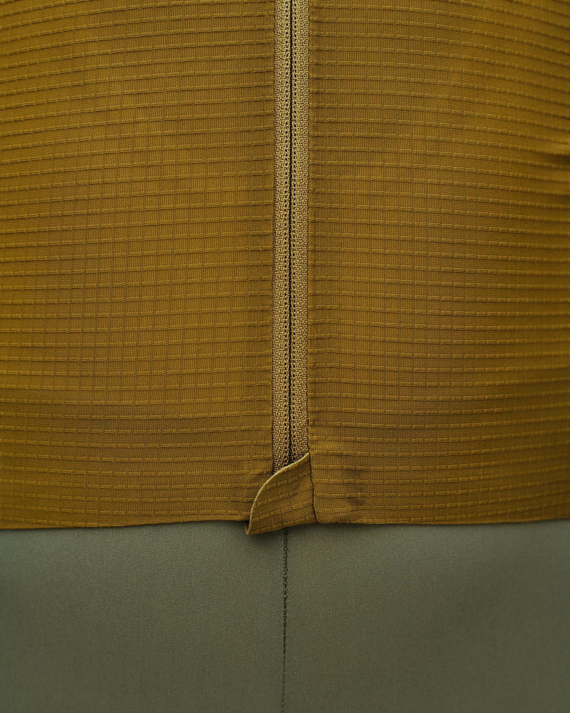 Close-up of mustard yellow ribbed fabric with central seam detail and green fabric below