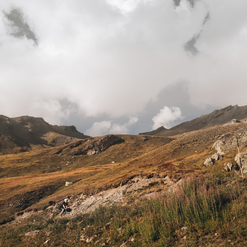 Rugged mountain landscape with golden grassland under cloudy sky
