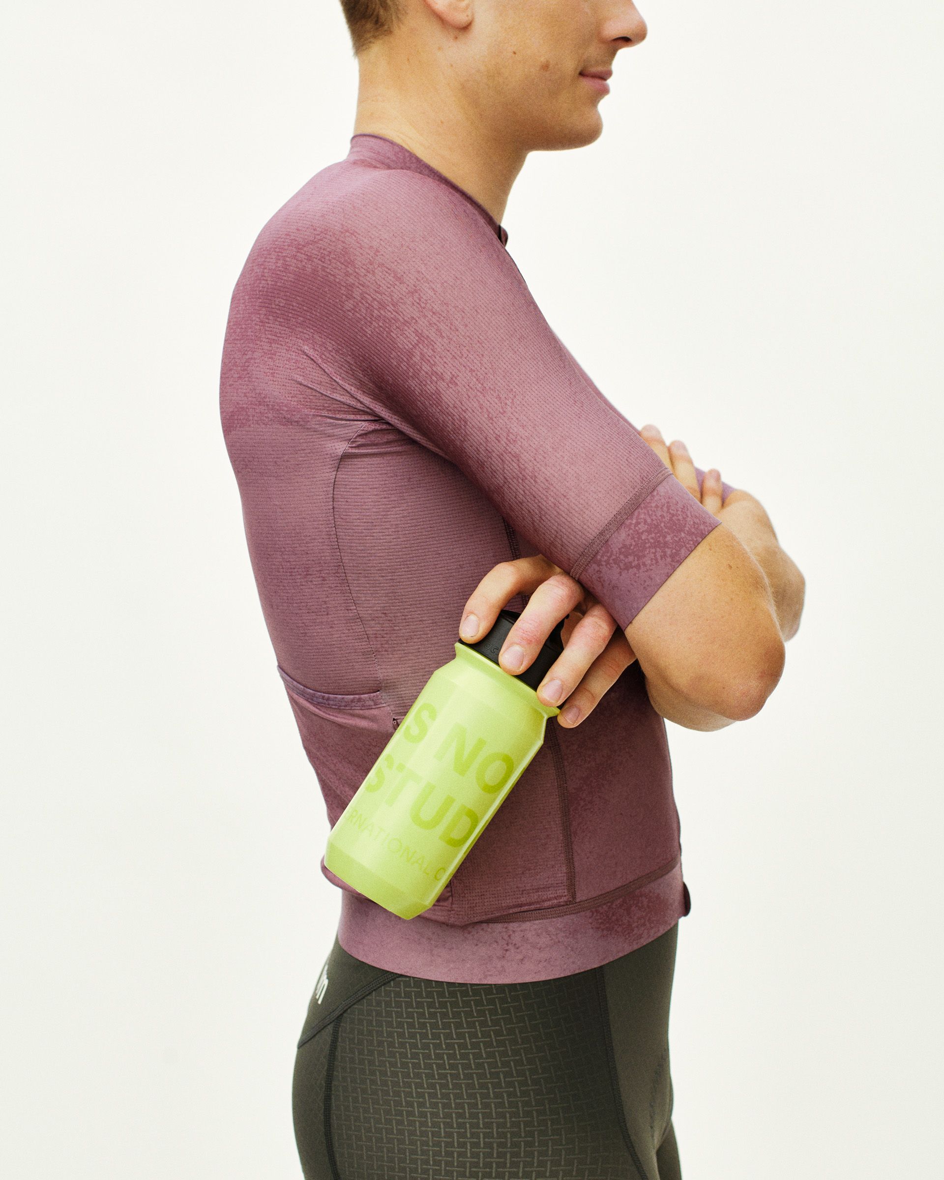 Green Essential Logo water bottle held by model in purple long sleeve top