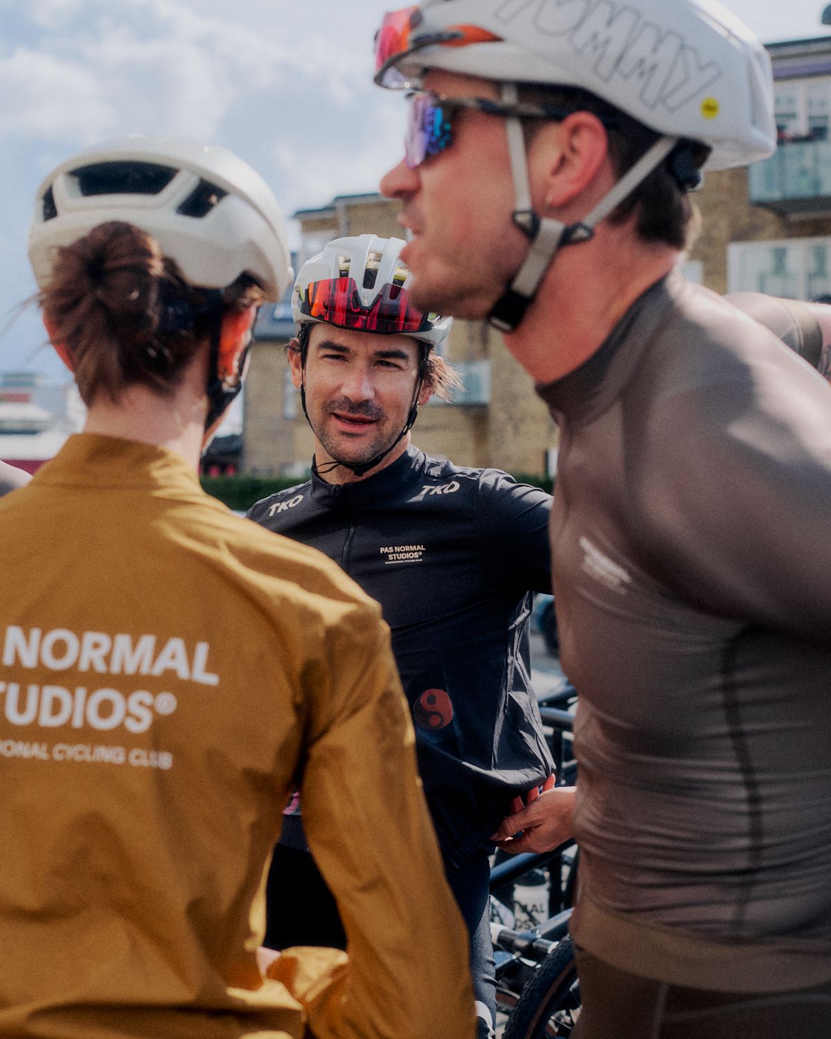 Cyclists wearing branded apparel and helmets gathered at outdoor cycling event