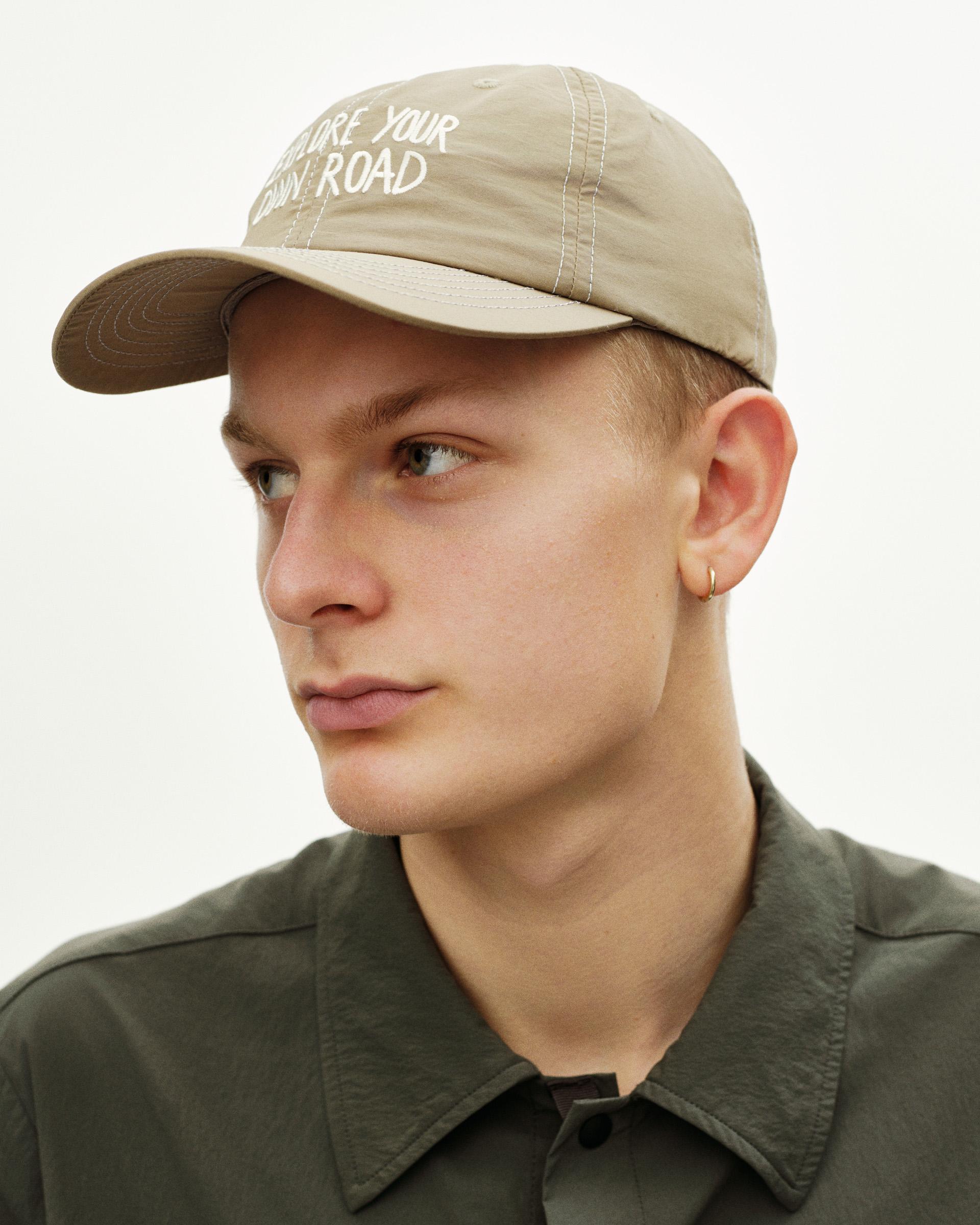 Beige Off-Race cap on model with white embroidered text