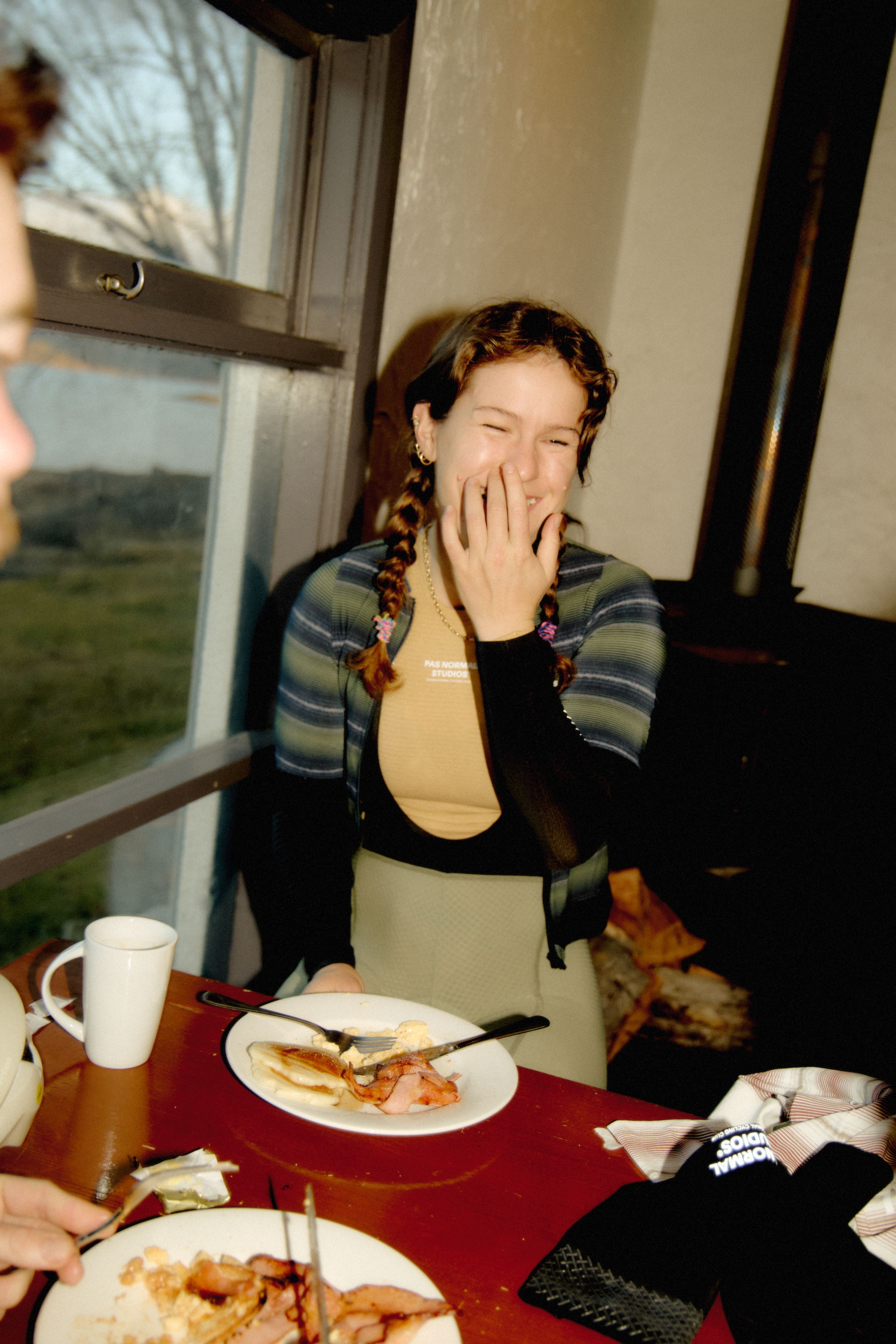 Model wearing Women's striped cardigan in green and black colorway while dining indoors