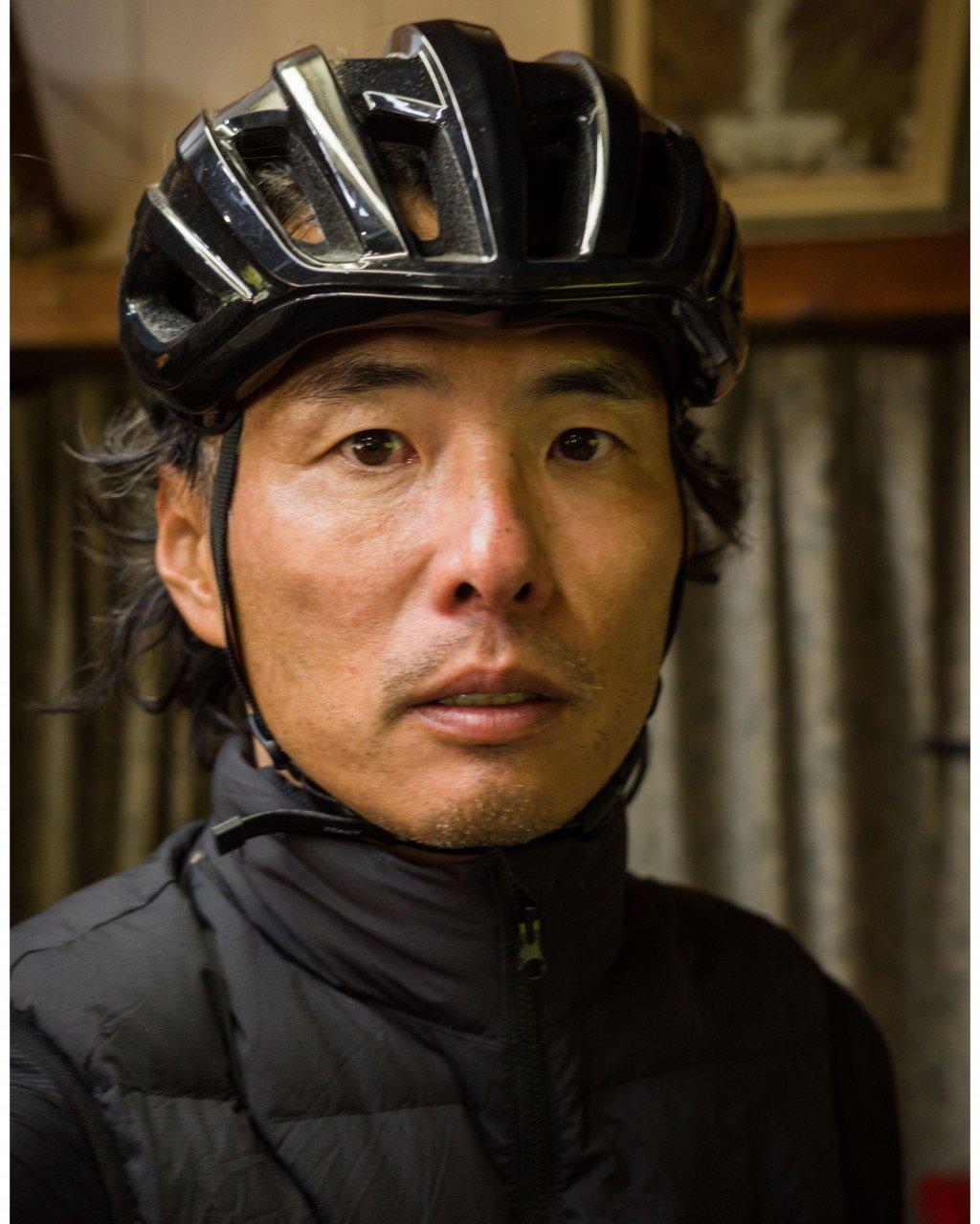 Model wearing black cycling helmet and dark jacket indoors