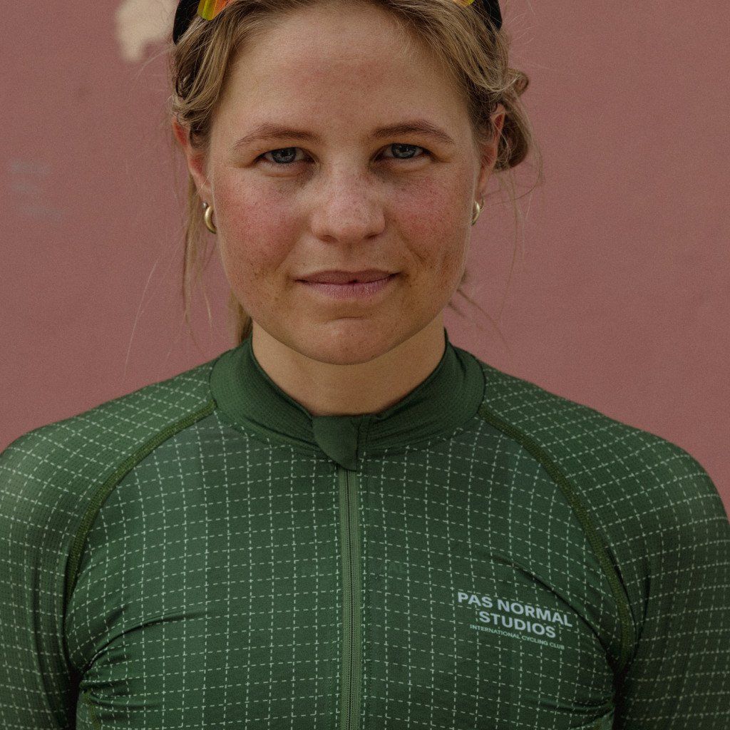 Model wearing green cycling jersey with white grid pattern and quarter zip