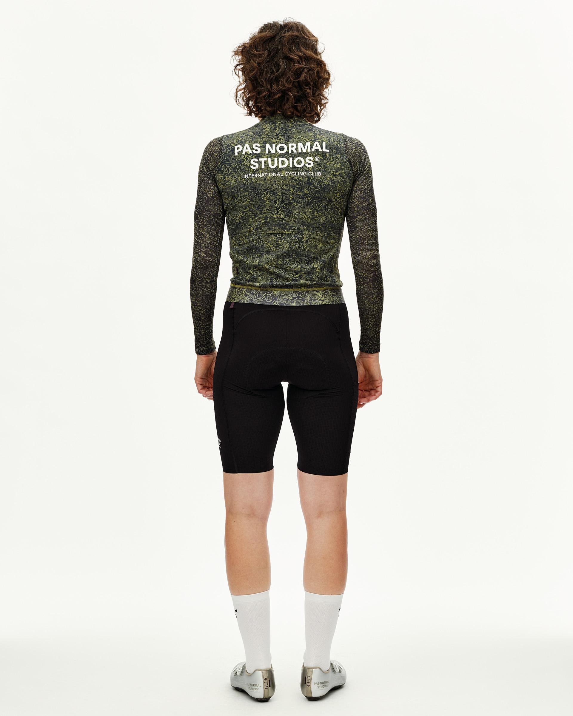 Dark Lime Essential long sleeve cycling jersey on model, rear view with all-over pattern print and white back logo