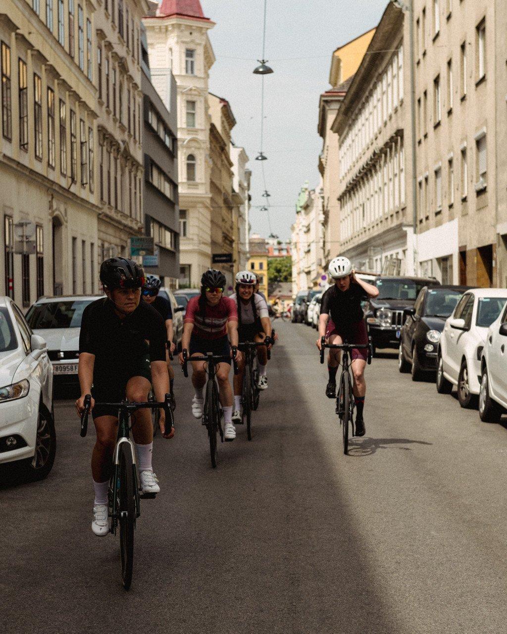 Group of cyclists riding through historic European city street in mixed cycling apparel